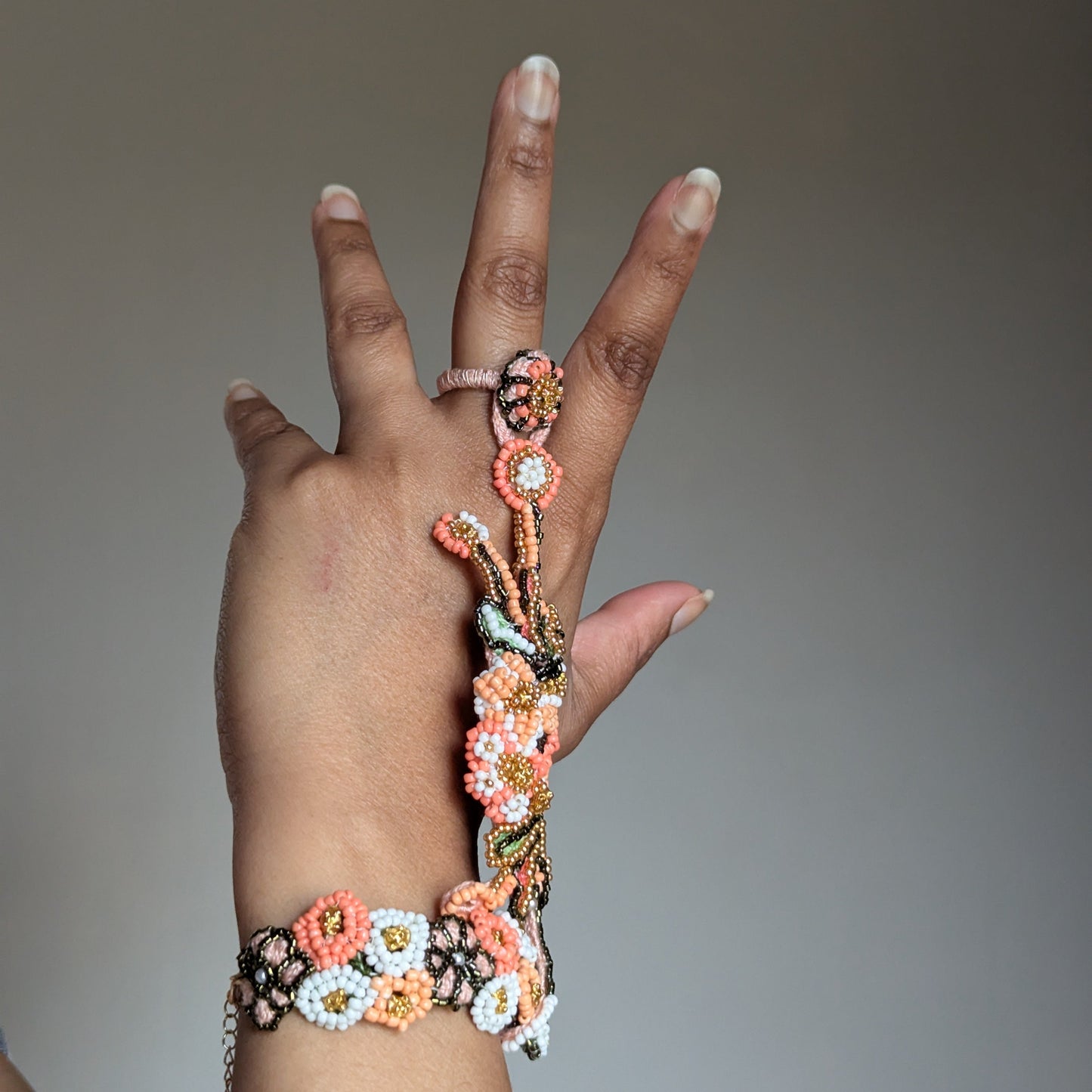 A hand modelling an intricately beaded handmade one of a kind Indian bracelet unique to Mayaani Jewellery UK and referred to as the Padmika 5-in-1.
