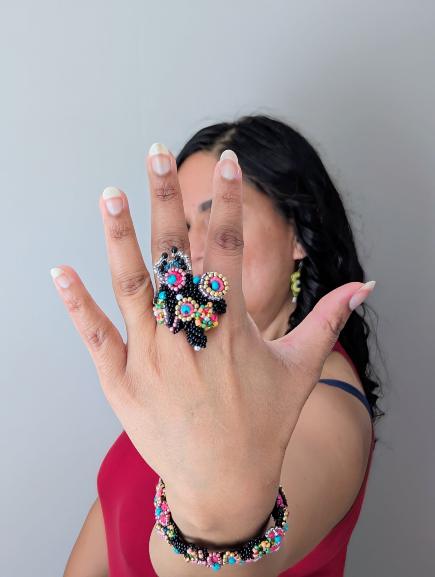 Model wearing the statement ring and bracelet elements of the signature Mayaani Jewellery Madhuri 5-in-1 Indian hand bracelet woven in black, blue, pink, gold and seed pearl accents.