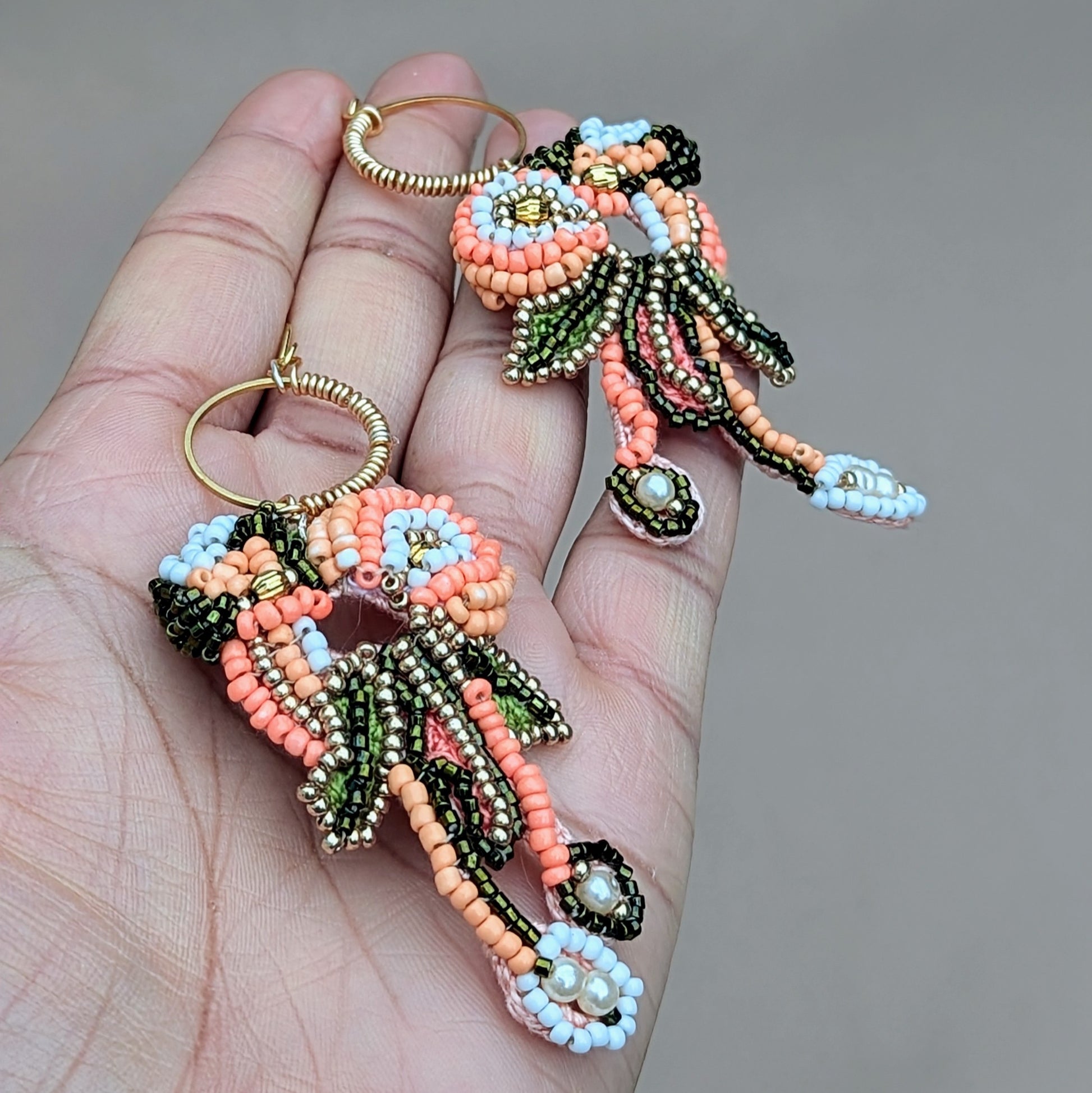 Padmika one-of-a-kind peach green and gold handmade Indian statement earrings, artisan beadwork with gold hoop, photographed in hand.