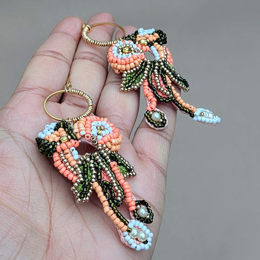 Padmika one-of-a-kind peach green and gold handmade Indian statement earrings, artisan beadwork with gold hoop, photographed in hand.