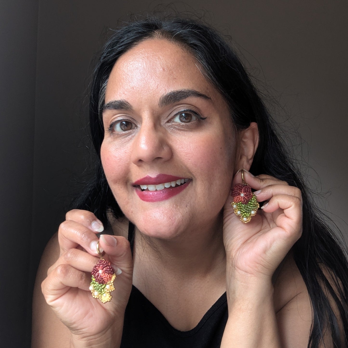 Mayaani Jewellery founder Megha wearing Rukmini handmade earrings - conscious luxury botanical drop earrings made in the UK featuring burgundy, olive, pearl and gold detailing.