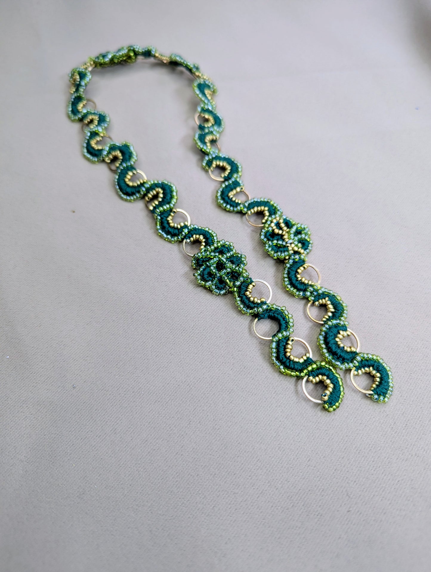 Flat lay image of an Indian designer made green and gold bead crochet chain exclusive to sustainable brand Mayaani Jewellery UK.
