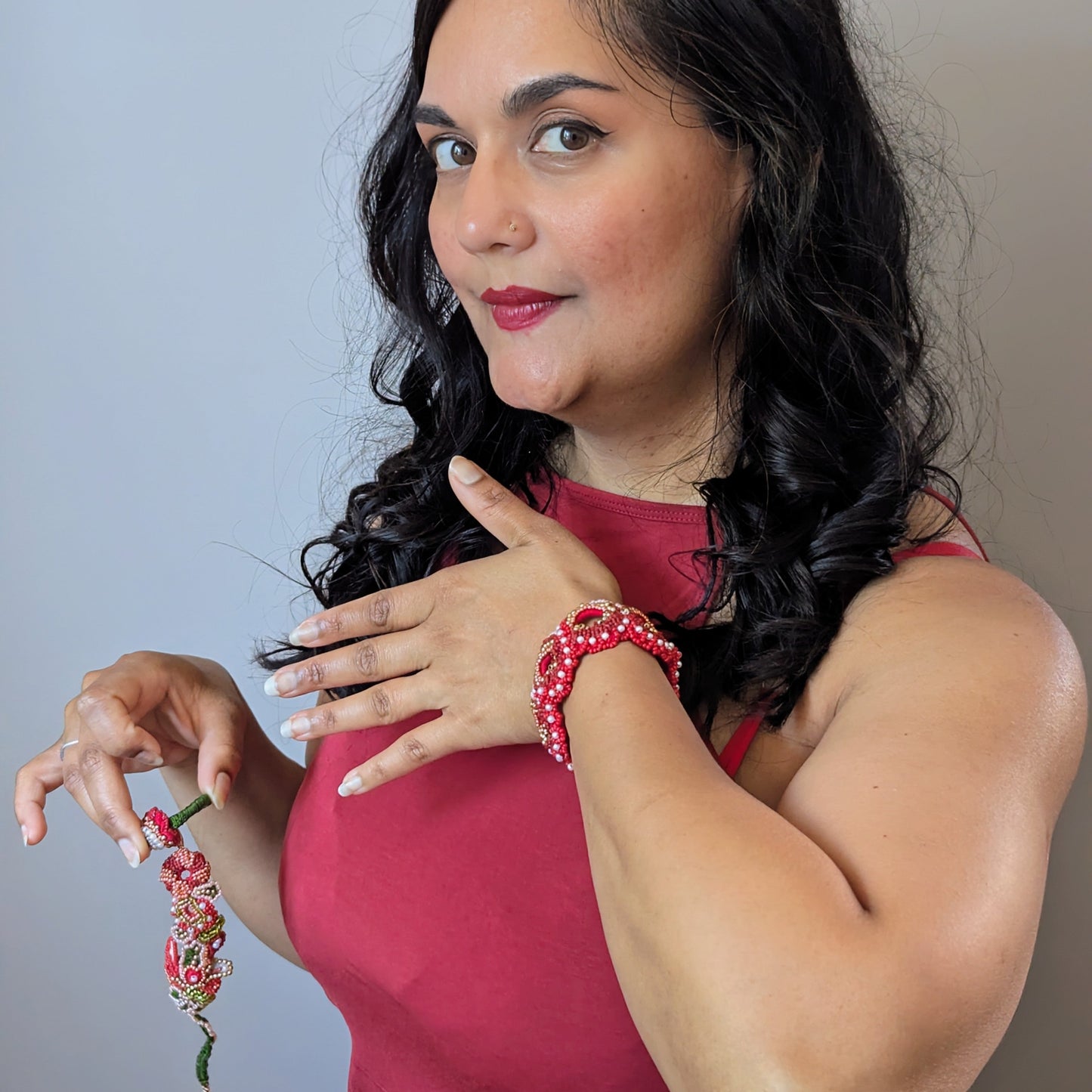 UK Indian artisan Megha holding the Shreya 5-in-1 ring and central element whilst wearing the statement wrist bracelet in red and gold.