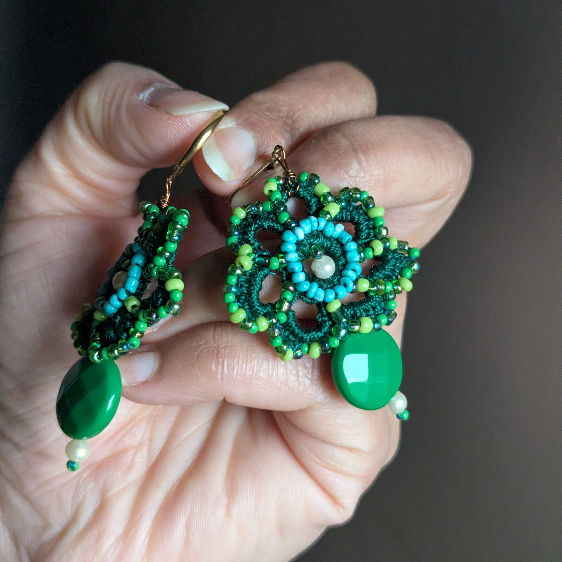 Front-facing view of green floral drop earrings with vintage beads and pearl cotton detailing, handmade in the UK.