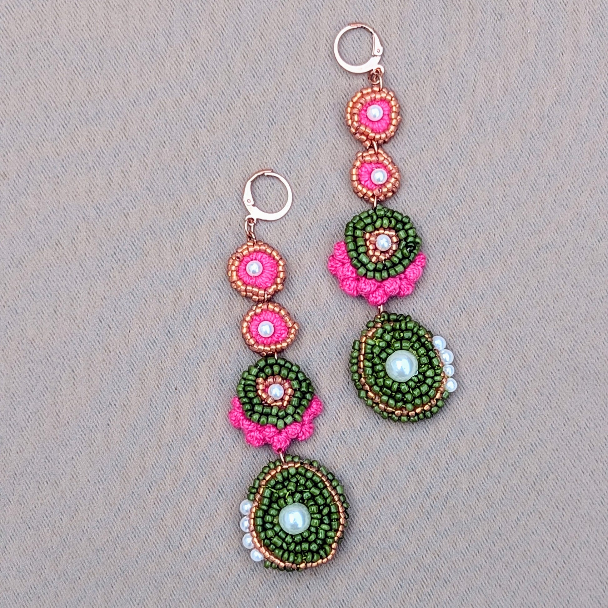 Flat lay of Minna handmade statement earrings featuring pink, green and pearl beaded detailing with circular and oval forms, handcrafted in the Uk by Mayaani Jewellery.