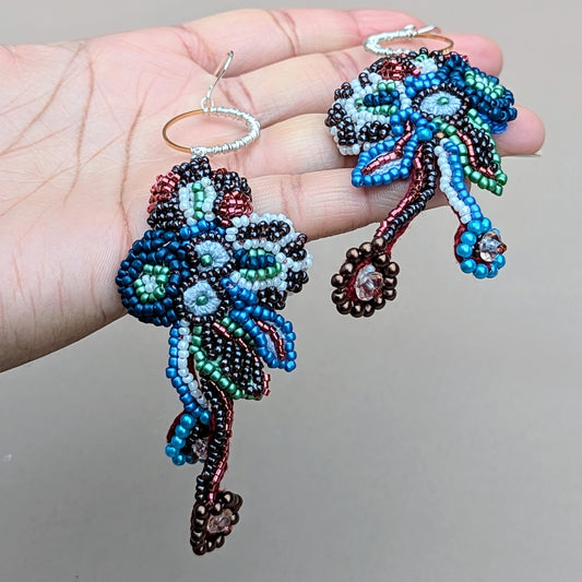 One-of-a-kind Neelara gold ring, red, blue, green, soft white beaded earrings, held in hand, handcrafted with crochet, wire wrapping and bead embroidery.