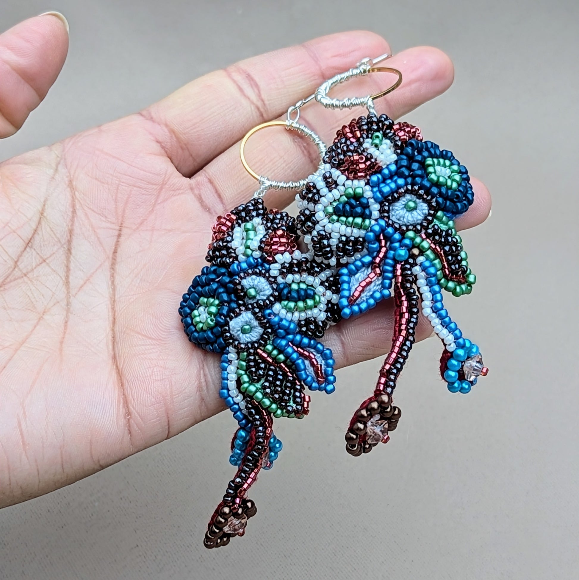 Handmade Neelara statement earrings by Mayaani Jewellery, showcasing cascading, red, blue and white bead embroidery with hand crochet and wire wrapping, designed for expressive, artistic wear.