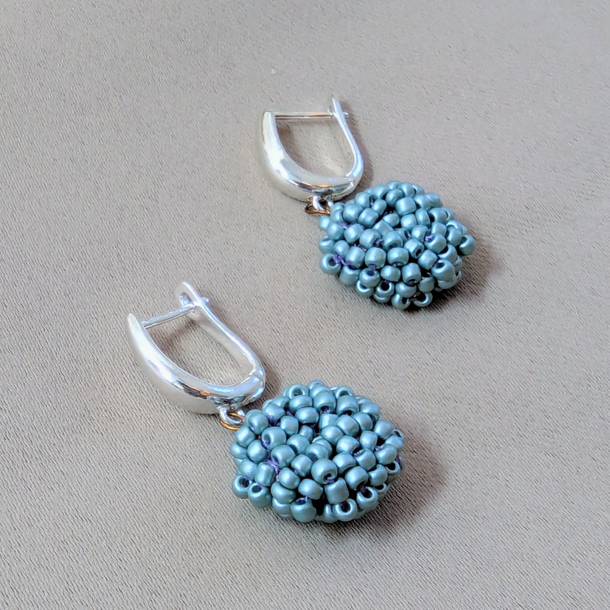 Soft sky blue beaded earrings resting on hand symbolising calm, care, and creativity.
