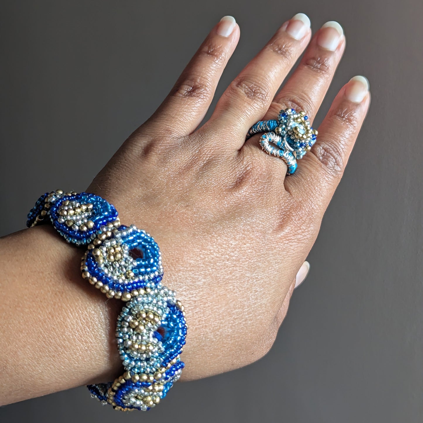 Nira handamde Indian 5-in-1 bracelet worn on wrist with Nira ring on middle finger - blue teal and gold one of a kind piece by Mayaani Jewellery UK.
