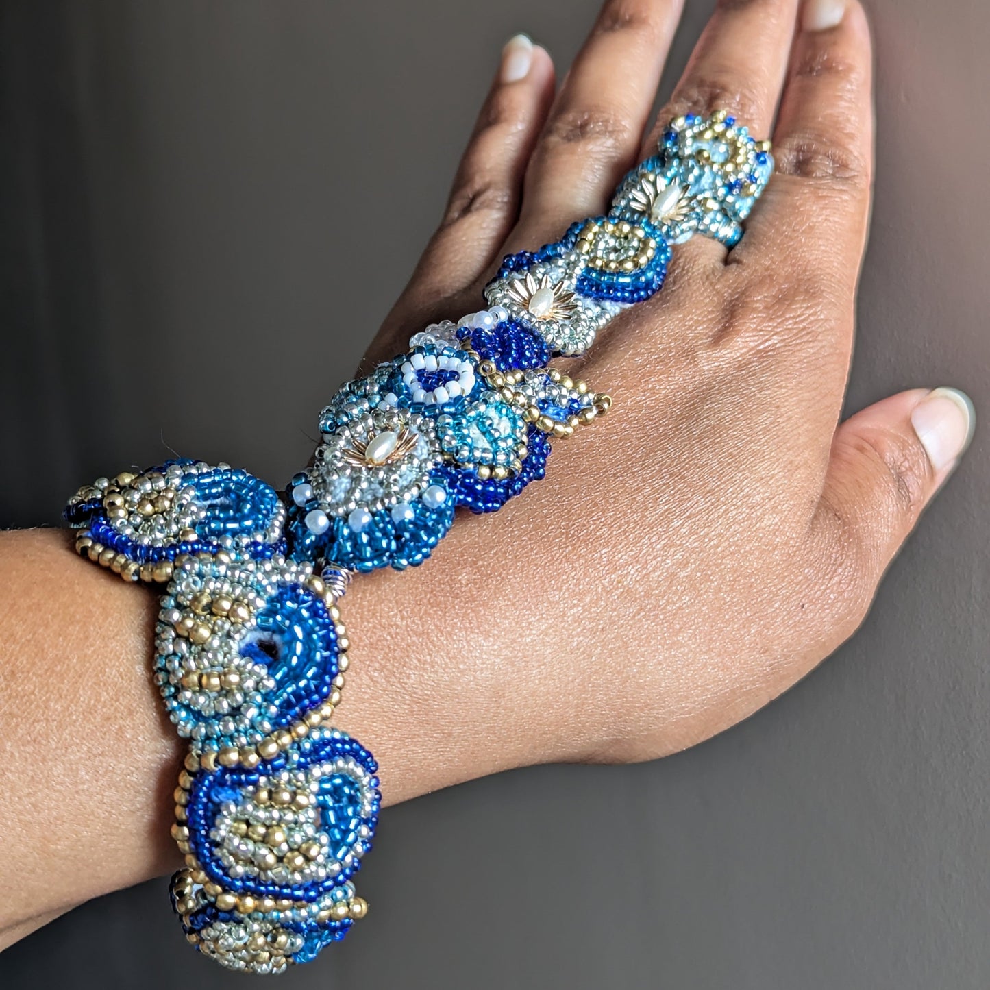 Full view of Nira 5-in-1 blue and gold luxury Indian statement hand bracelet modelled worn on a hand against a neutral backdrop.