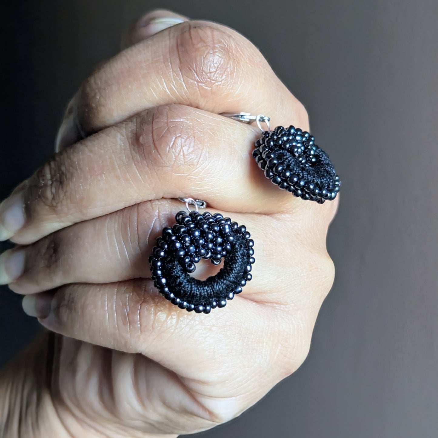 Close-up of handmade black beaded Indian-style earrings crafted with crochet and vintage seed pearls.