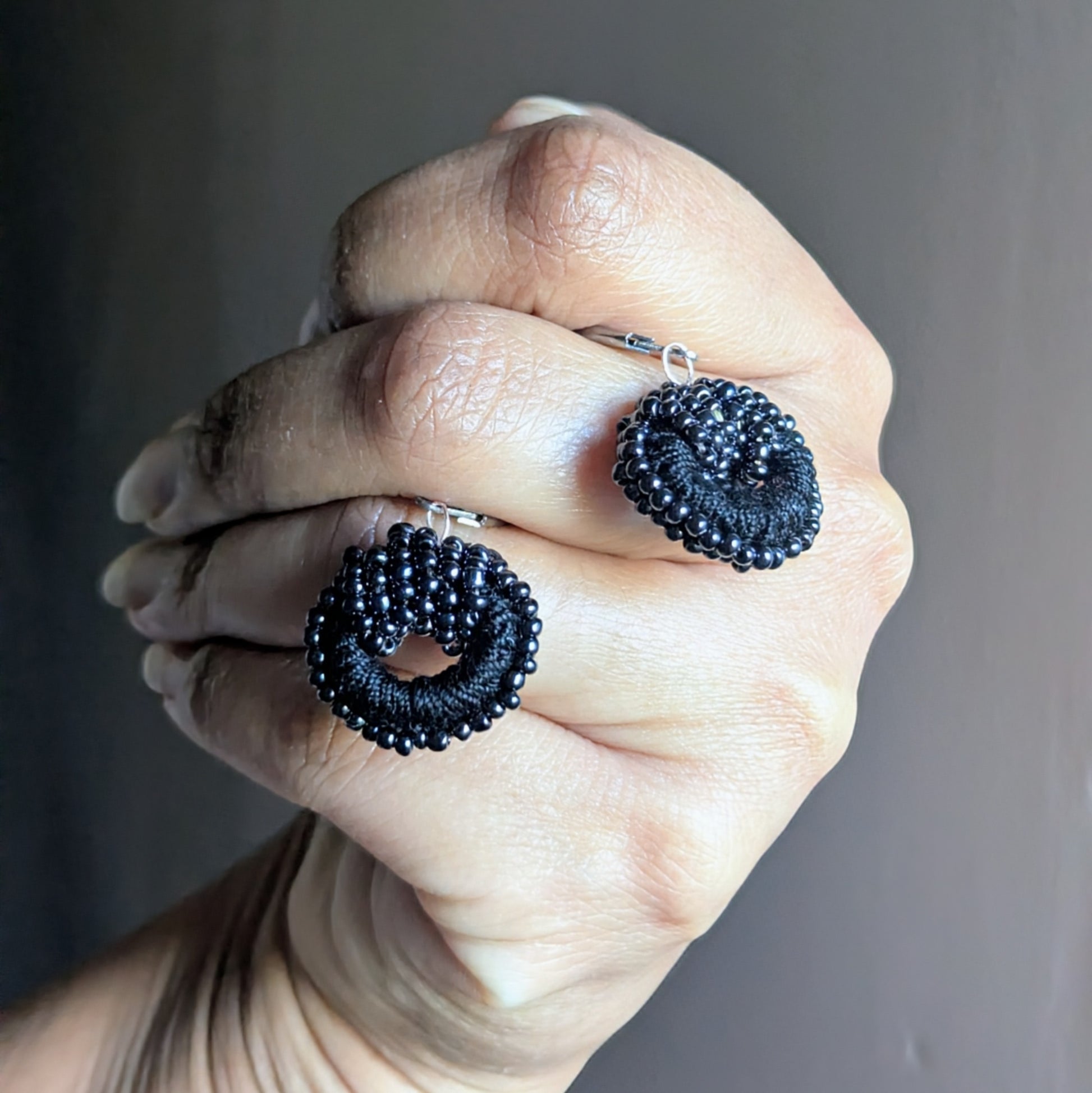 Lightweight handmade black bead earrings with domed crochet centres and pearl details.
