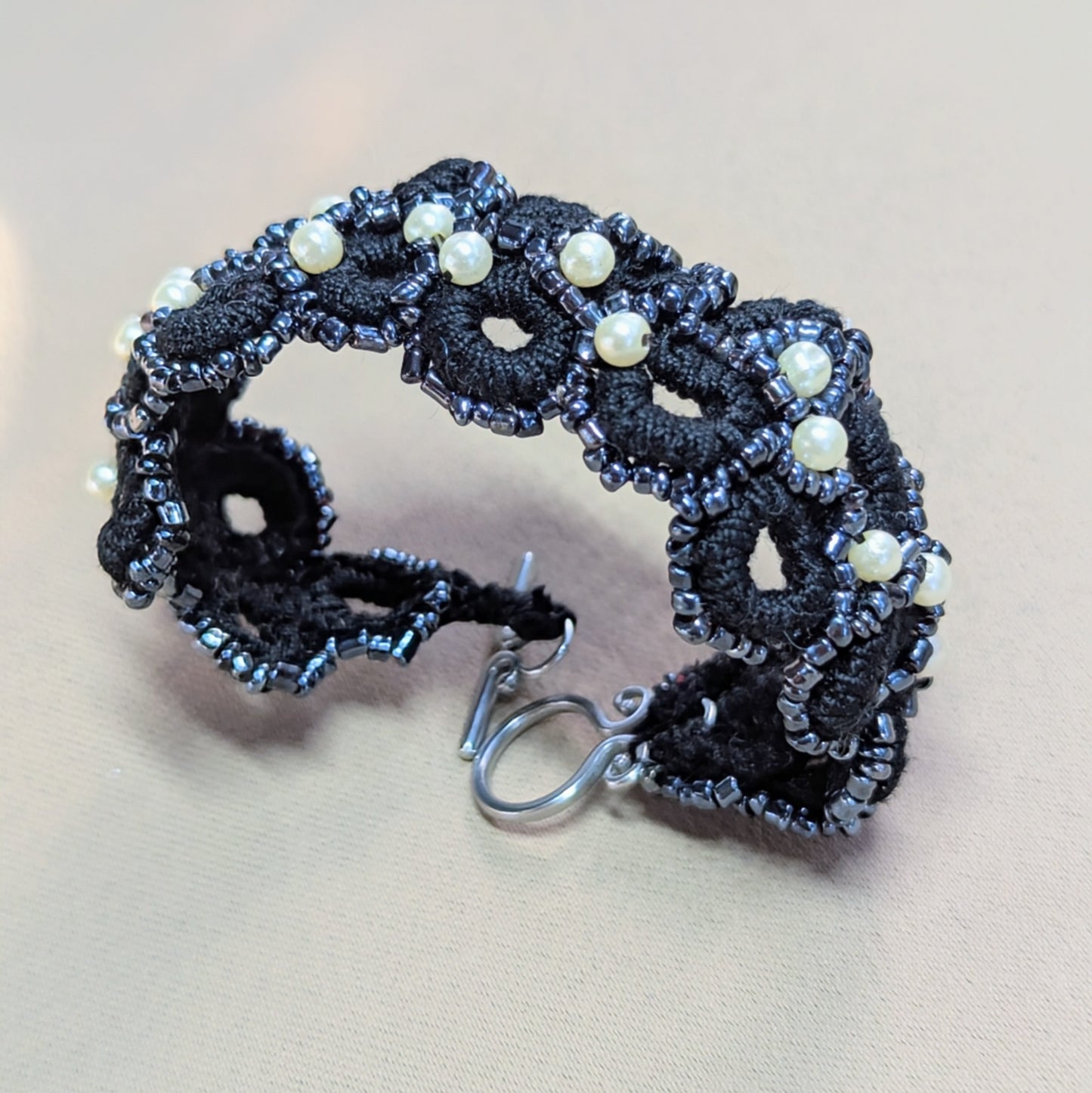 Nisha black crochet bracelet displayed against a neutral backdrop, highlighting the continuous woven design and soft beaded edges.