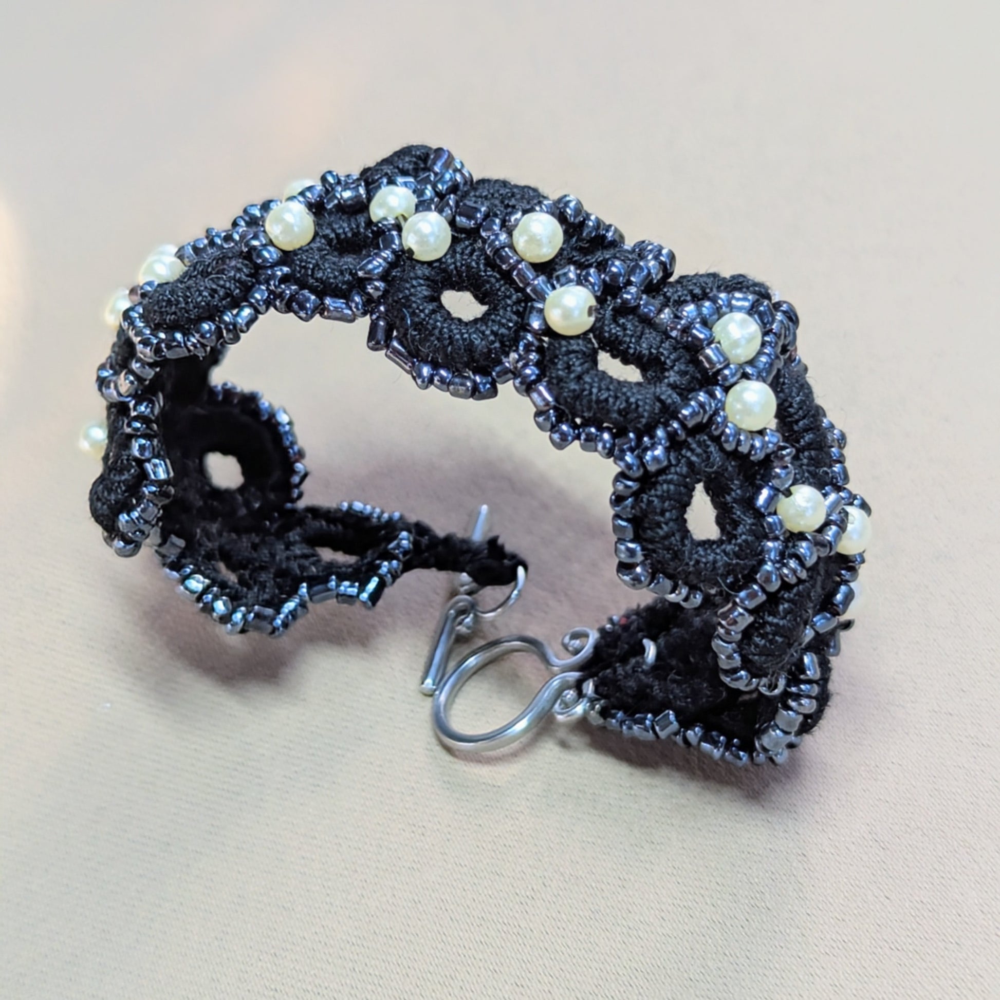 Nisha black crochet bracelet displayed against a neutral backdrop, highlighting the continuous woven design and soft beaded edges.