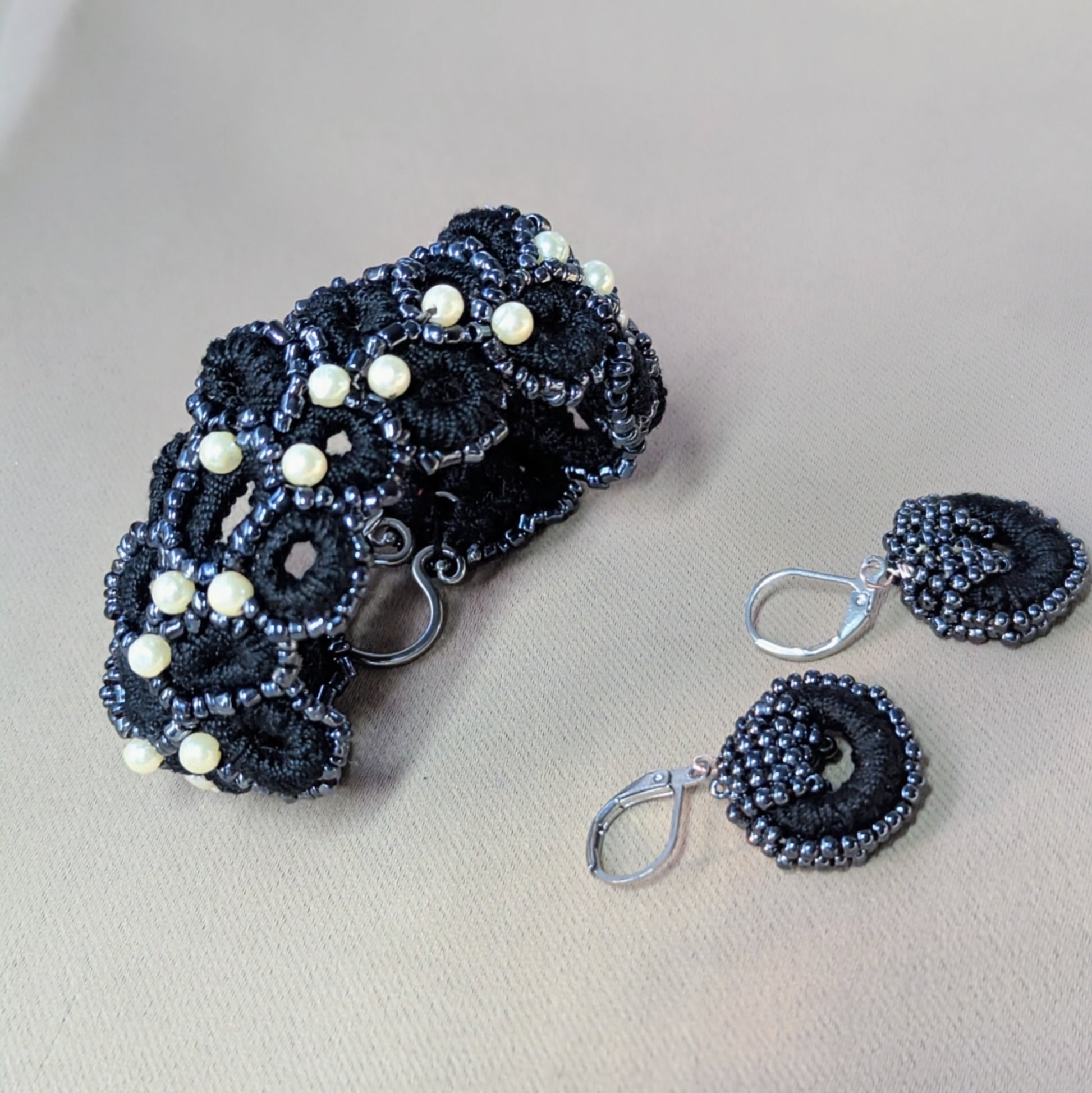 Artisan-made black beaded bracelet and earrings featuring vintage pearls and crochet lace detailing.