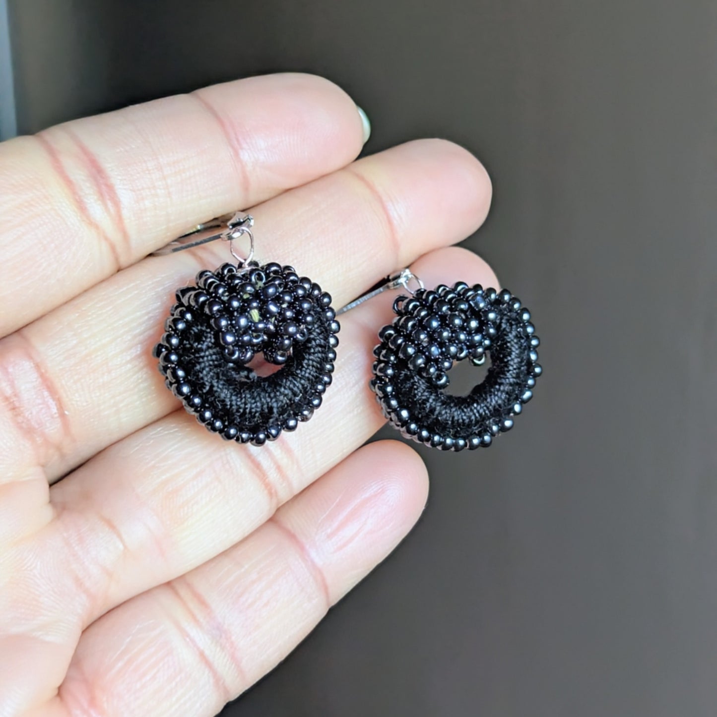 One-of-a-kind black beadwork earrings with vintage pearls displayed in hand.