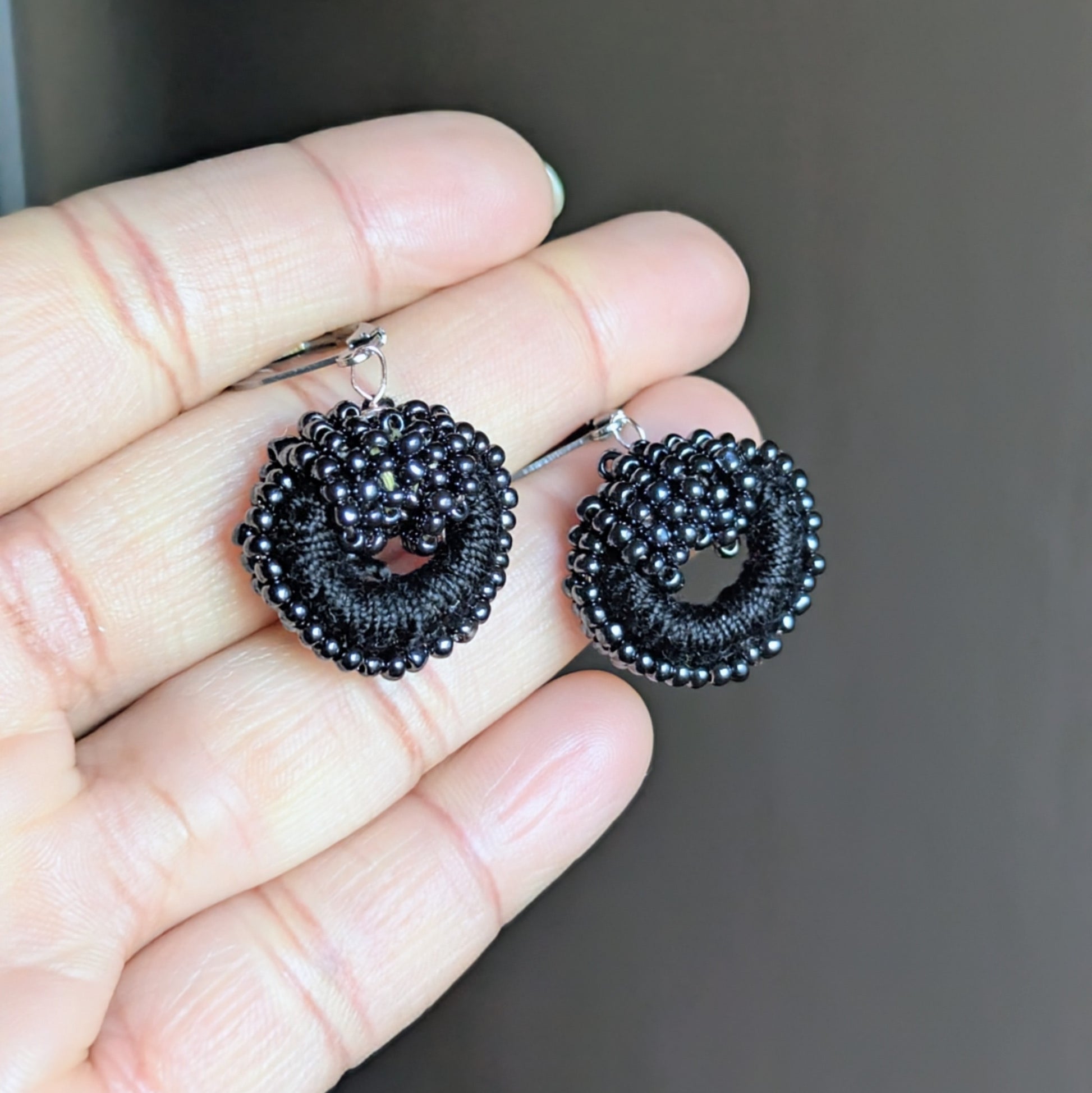 One-of-a-kind black beadwork earrings with vintage pearls displayed in hand.