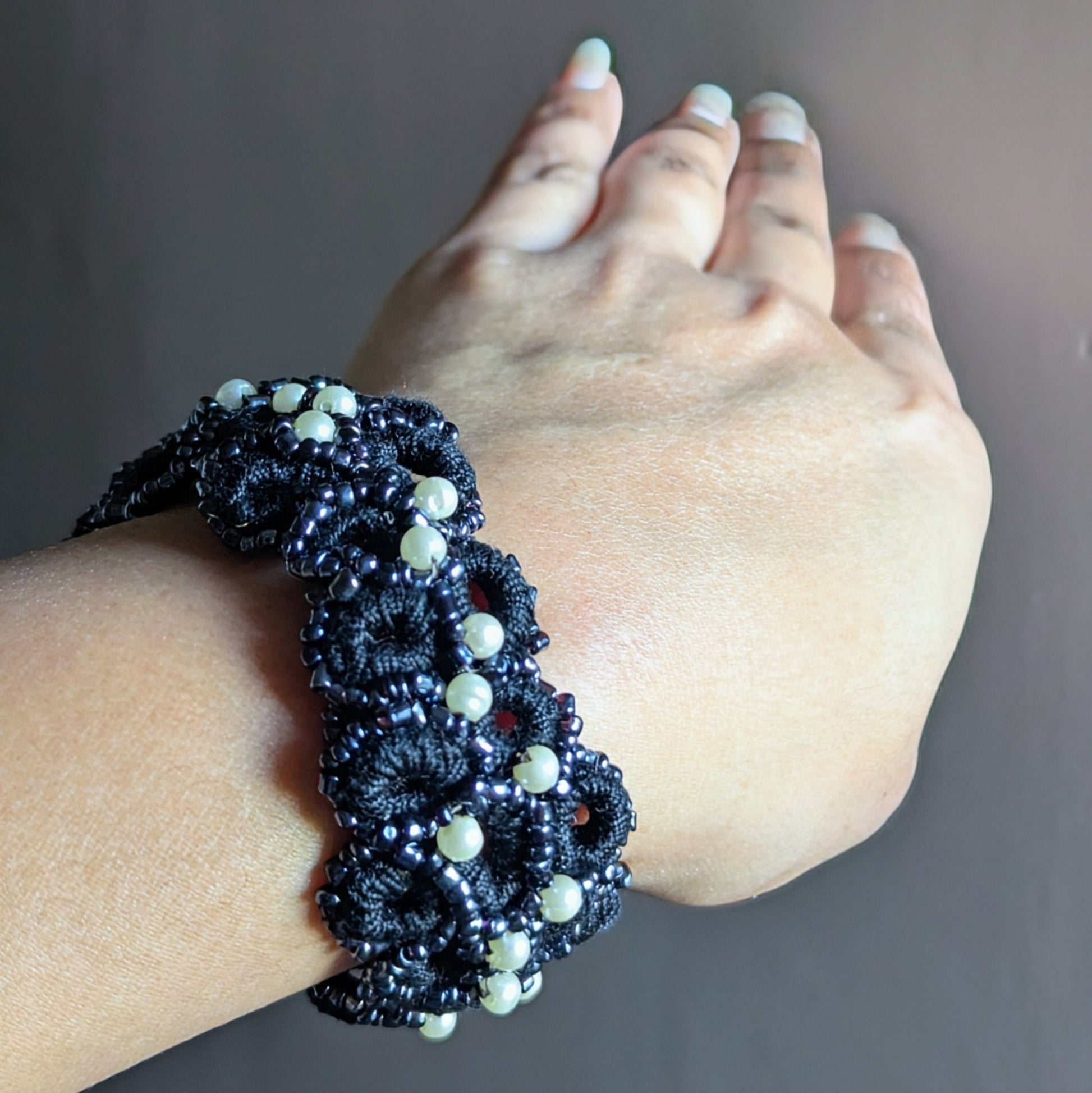 Handmade black and pearl beaded crochet bracelet wrapped around the wrist, finished with a stainless steel toggle clasp.