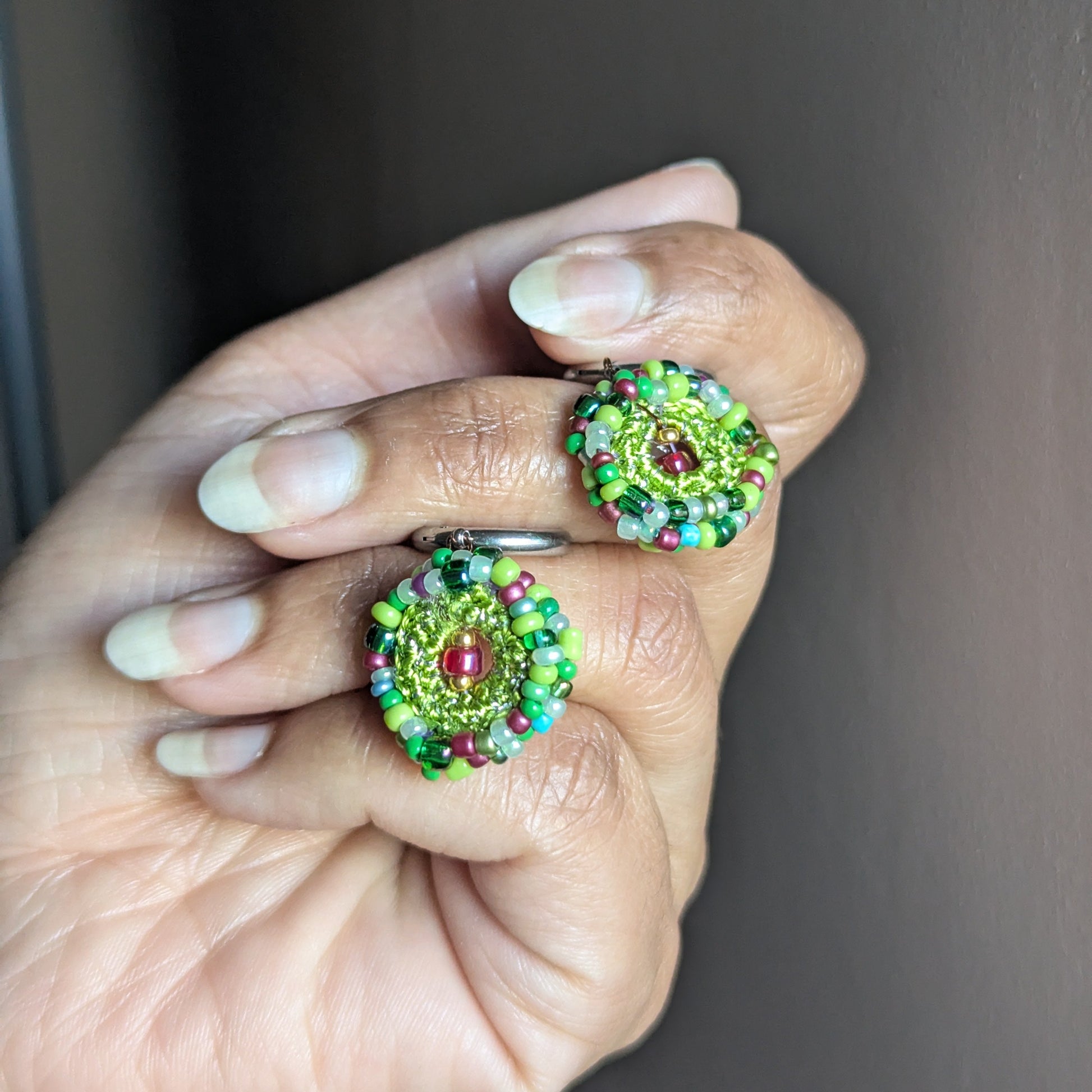 Side profile of Vana handmade bead crochet earring held in hand, revealing depth, texture, and dimensional layering of the circular design.