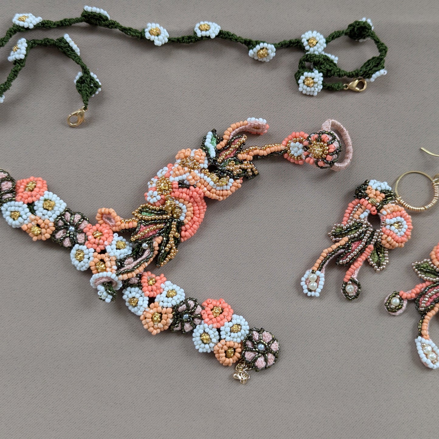 Flat lay of a one of a kind Padmika hand bead woven Indian jewellery set in peach, green, gold and white featuring vintage upcycled beads. Made in the UK.