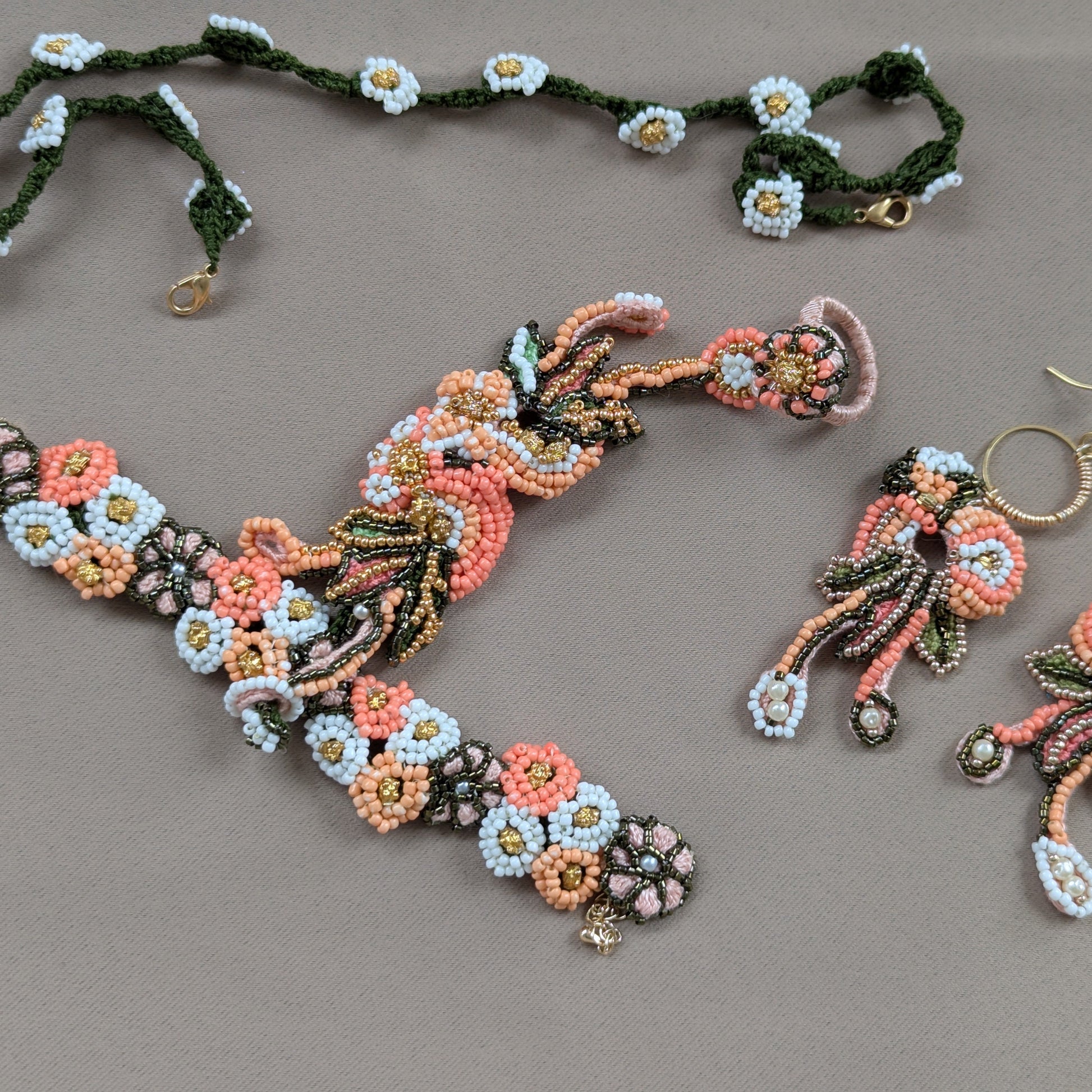 Flat lay of a one of a kind Padmika hand bead woven Indian jewellery set in peach, green, gold and white featuring vintage upcycled beads. Made in the UK.