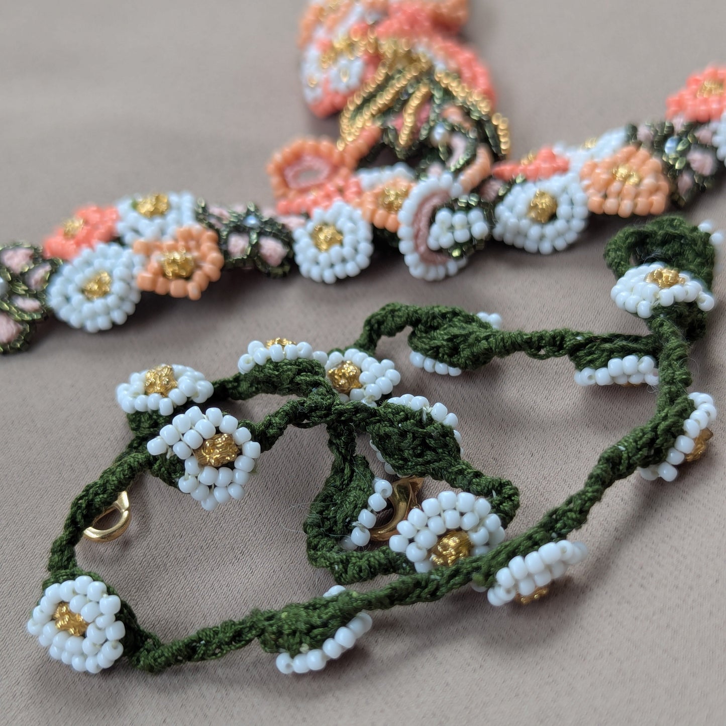 Close up view of the Padmika 5-in-1 custom chain featuring green crochet and white and gold bead work in floral motifs. Pictured with the Padmika 5-in-1 Indian hand bracelet visible in the backdrop.