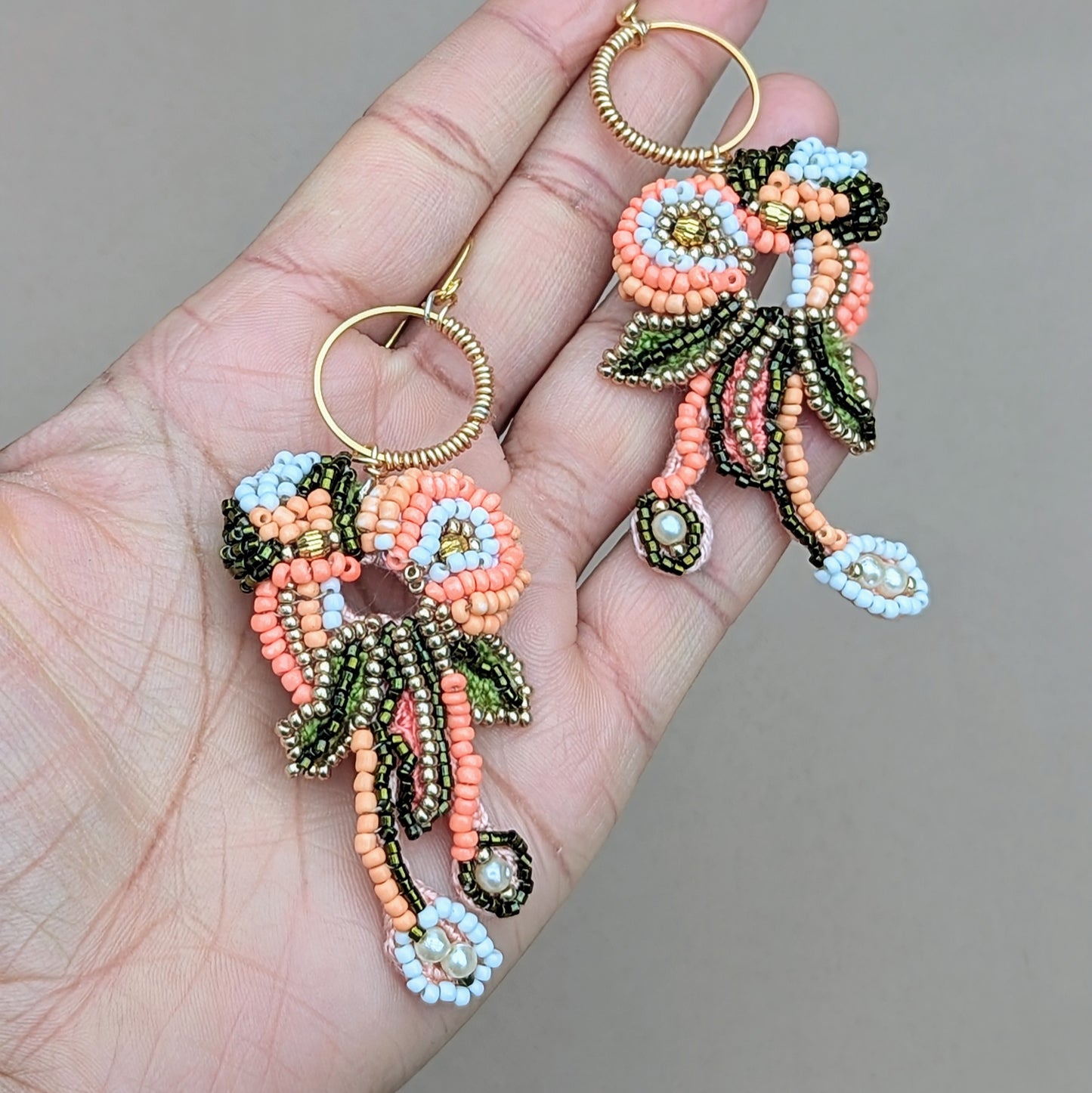 Side view of Padmika Indian statement earrings, in hand, highlighting layered bead strands, gold hoop and handcrafted movement.