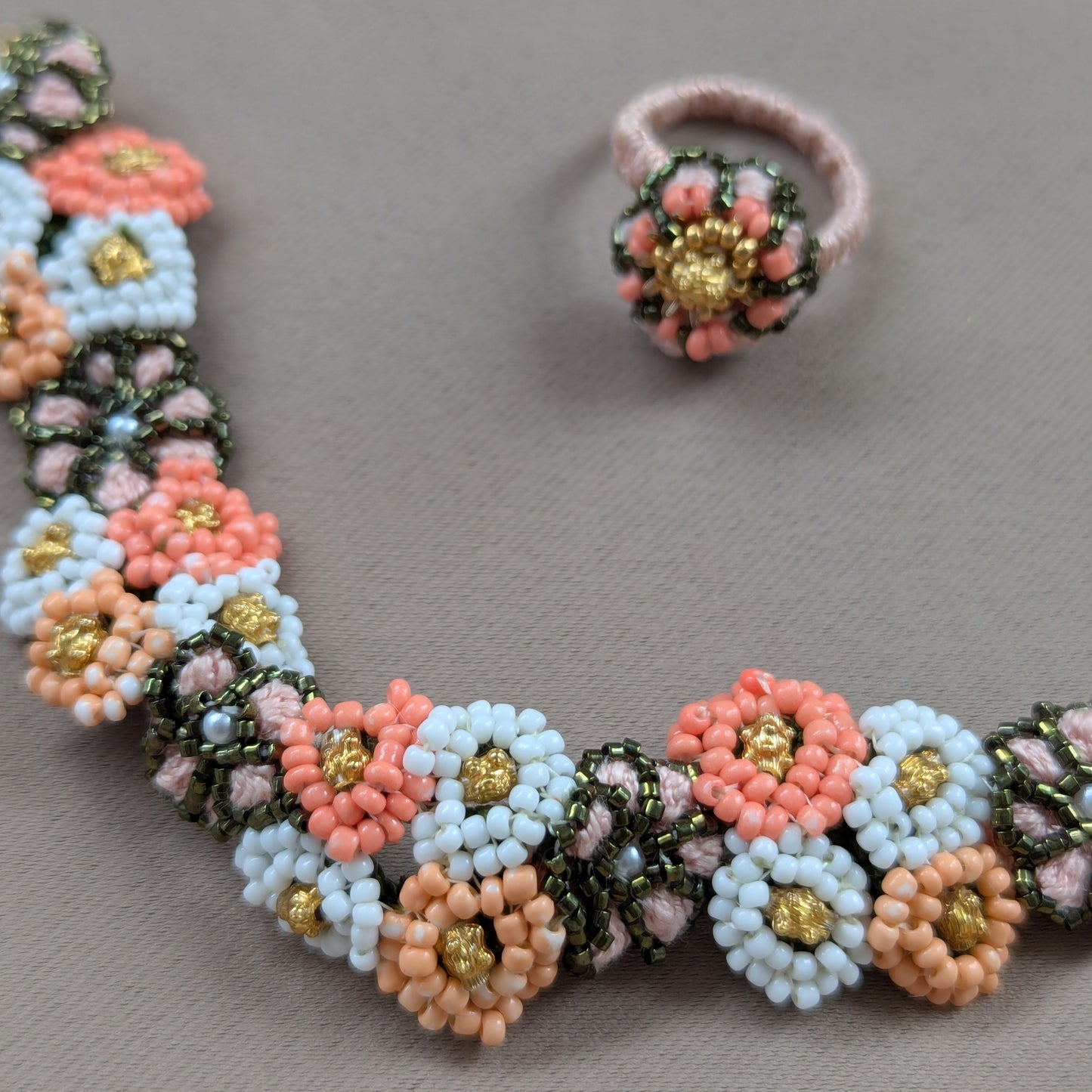 Detailed view of the Padmika 5-in-1 Indian hand bracelet separate wring and wrist bracelet elements intricately bead woven in peach, green and white seed beads including vintage gold beads.