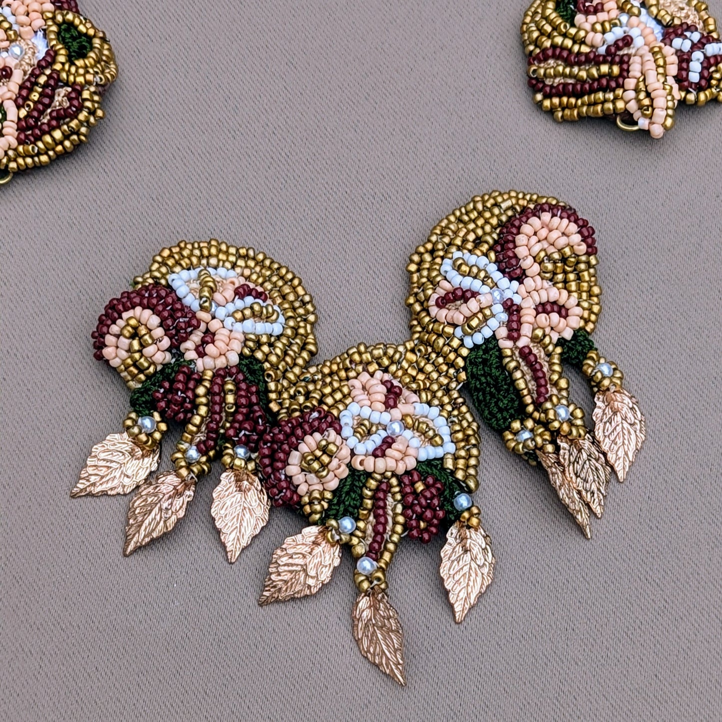 Close up view of detachable red, green and gold pendant exclusive to the Aishwarya bridal collection at Mayaani Jewellery UK celebrating Indian artistry, sustainability and cultural fusion.