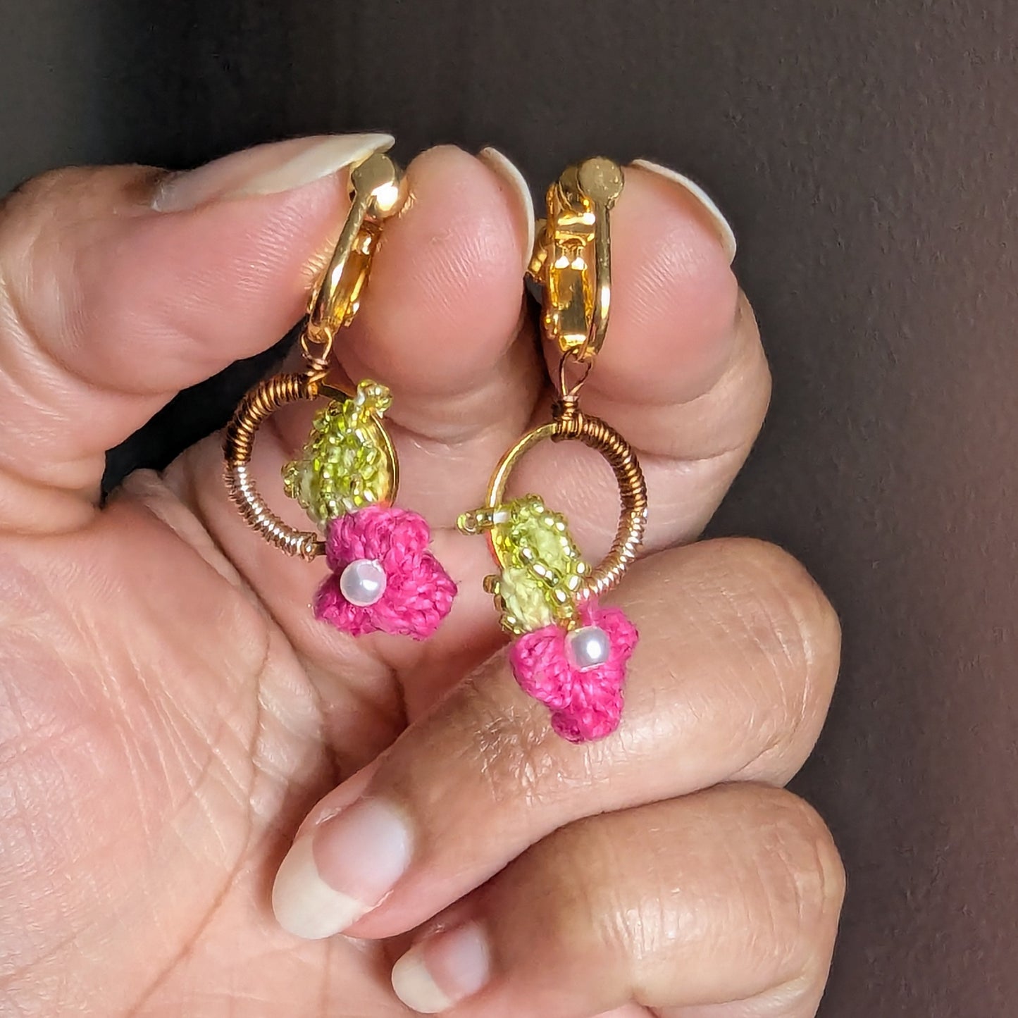 Detailed close up view of a small comfortable stainless steel clip-on clasp pair of floral pink, chartreuse green and gold Pallavi earrings from Mayaani Jewellery UK.