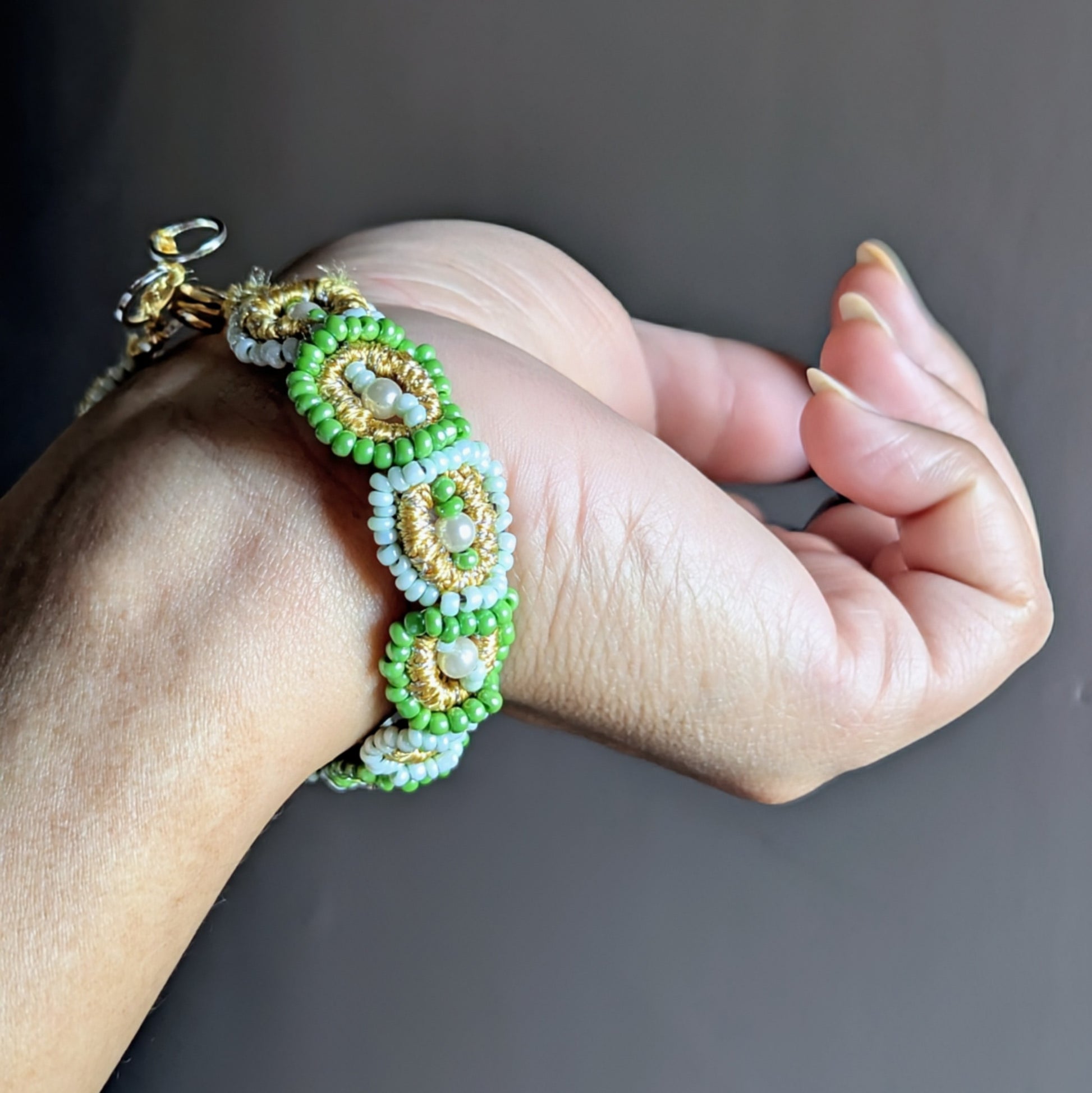 Artisan-made green beaded bracelet featuring handwoven motifs, triple-mercerised cotton, and a gold-plated clasp.