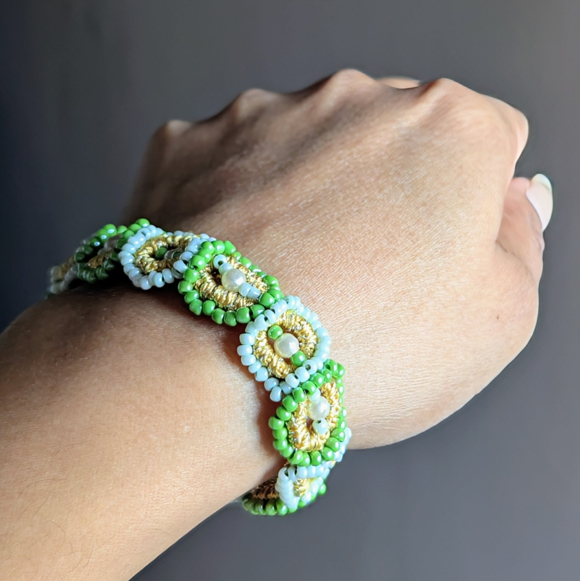 One-of-a-kind green and pearl bracelet featuring handwoven motifs and premium gold findings.