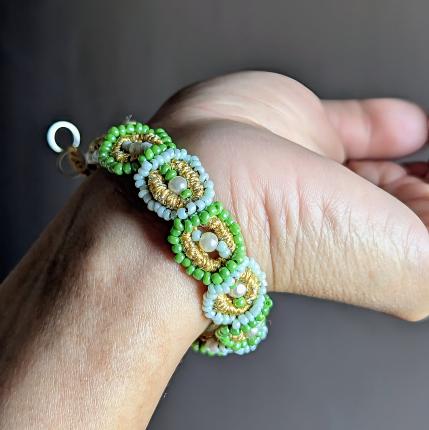 Handmade green beaded bracelet with gold pearl cotton and upcycled seed pearls — sustainable fine jewellery.
