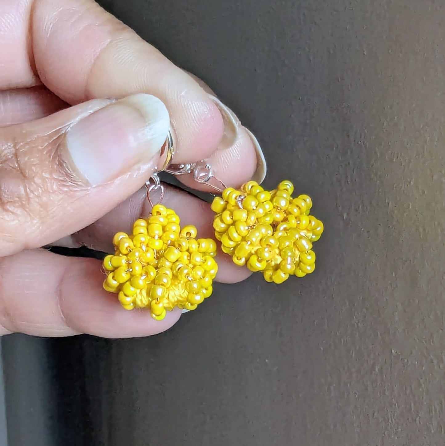 Hand holding the Raiya earrings - lightweight yellow beaded hoops ready to wear for everyday through to occasion wear.