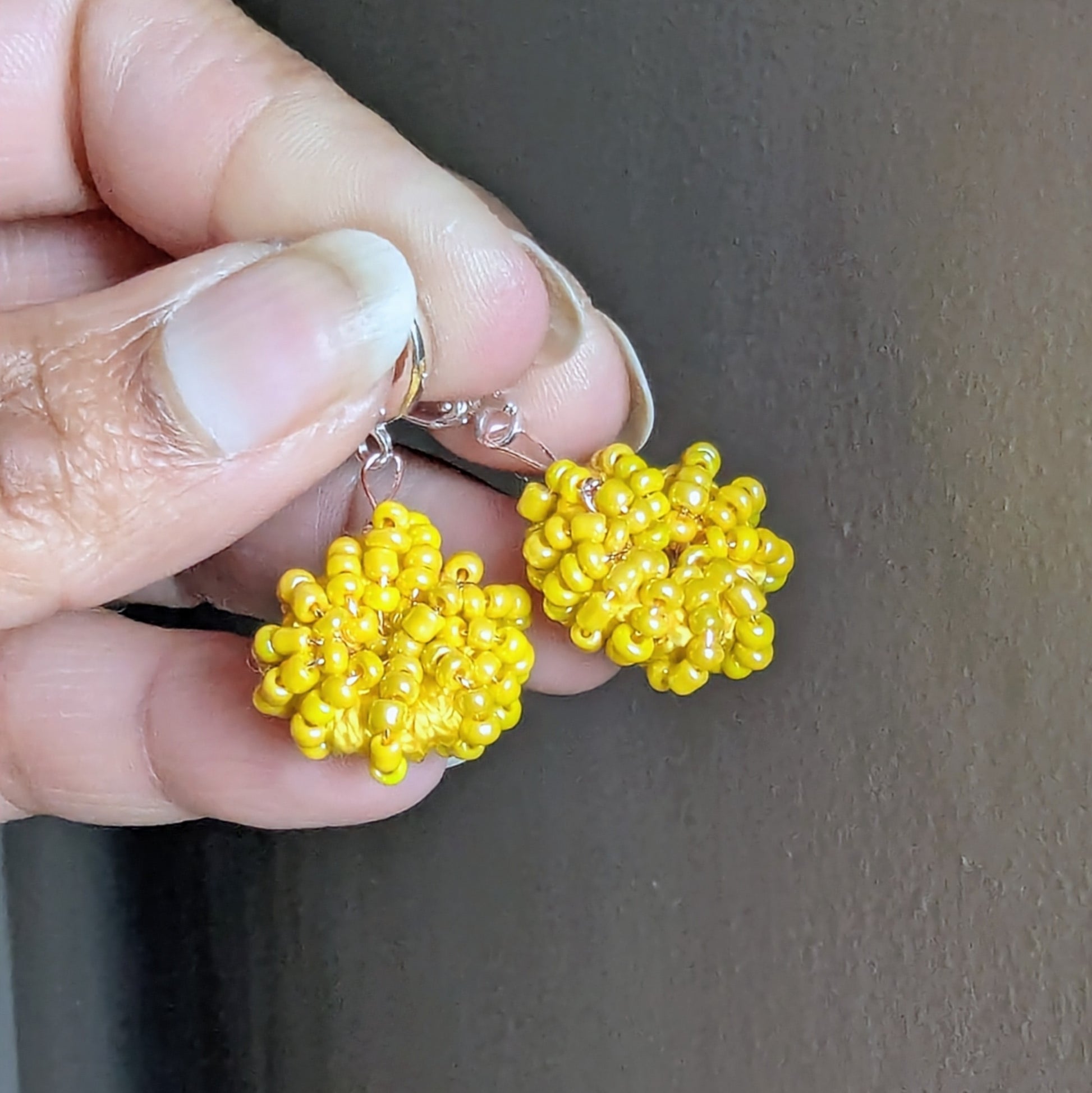 Hand holding the Raiya earrings - lightweight yellow beaded hoops ready to wear for everyday through to occasion wear.
