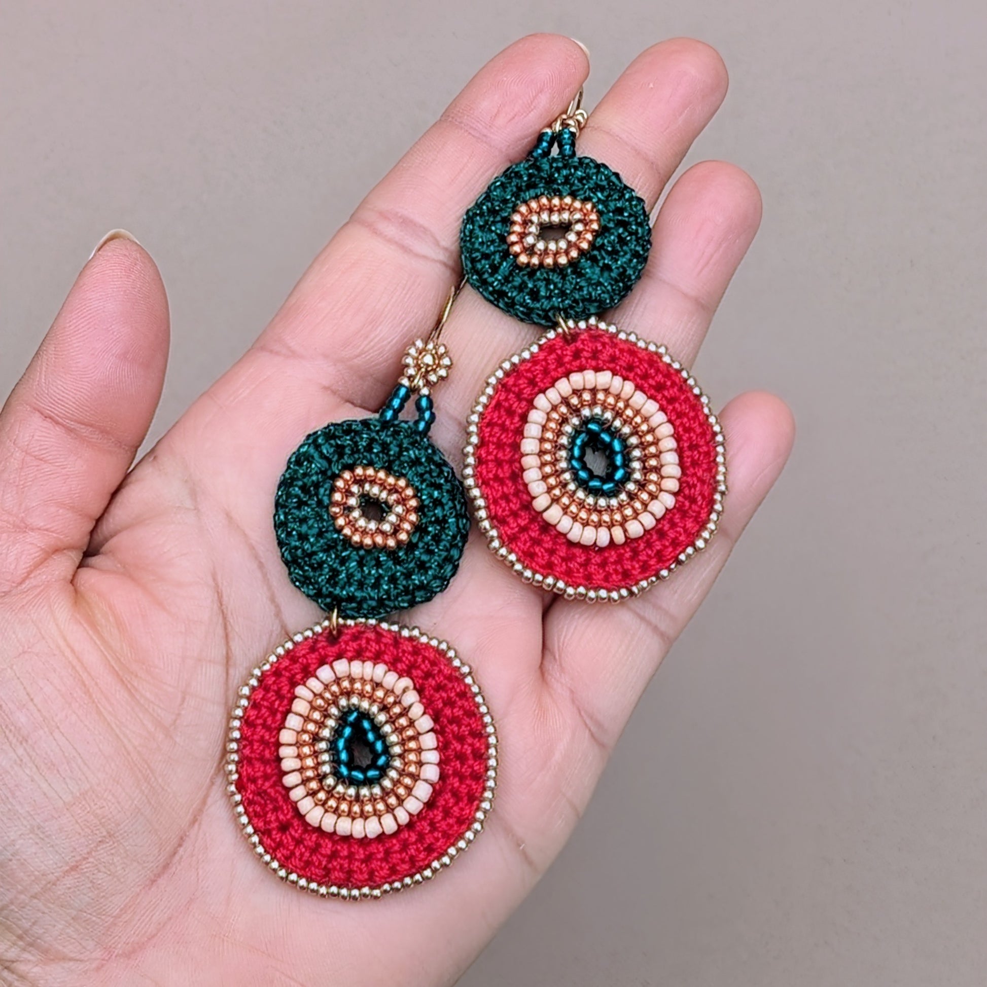 A handmade pair of colourful red, green, gold Indian heritage inspired earrings featuring circular crochet bead elements. Designed exclusively for Mayaani Jewellery to embrace luxury, comfort and artistry in one piece.