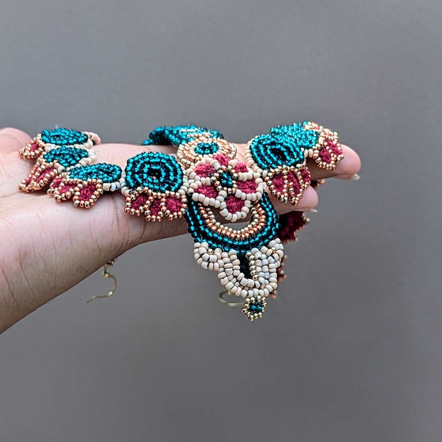 Unique bridal headpiece in traditional Indian style, created with circular bead motifs in emerald green, red, and gold with delicate handcrafted crochet and sustainable design.
