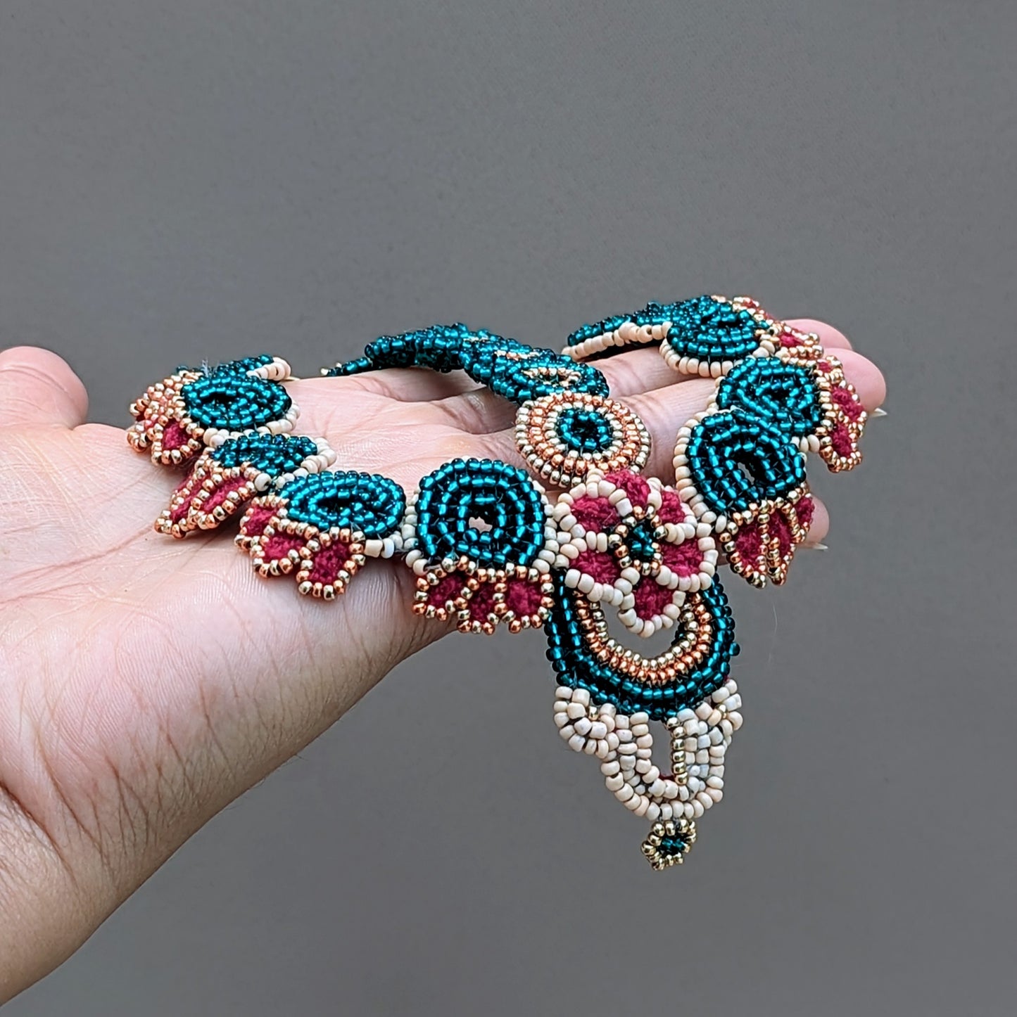 Artisan-made Indian bridal headpiece in traditional Indian style, created with circular bead motifs in emerald green, red, peach and gold seed beads handmade by Megha at Mayaani Jewellery UK.