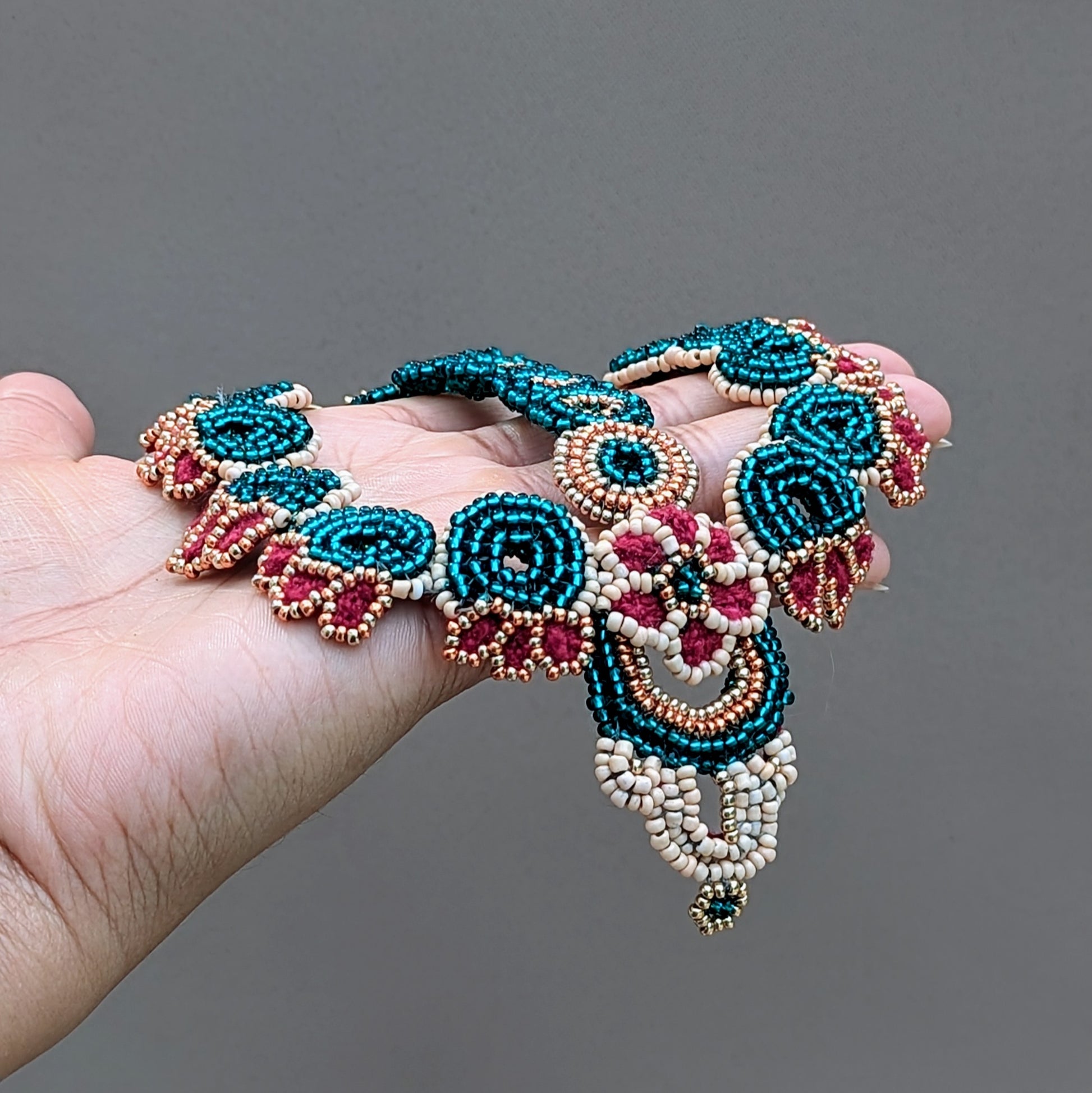 Artisan-made Indian bridal headpiece in traditional Indian style, created with circular bead motifs in emerald green, red, peach and gold seed beads handmade by Megha at Mayaani Jewellery UK.