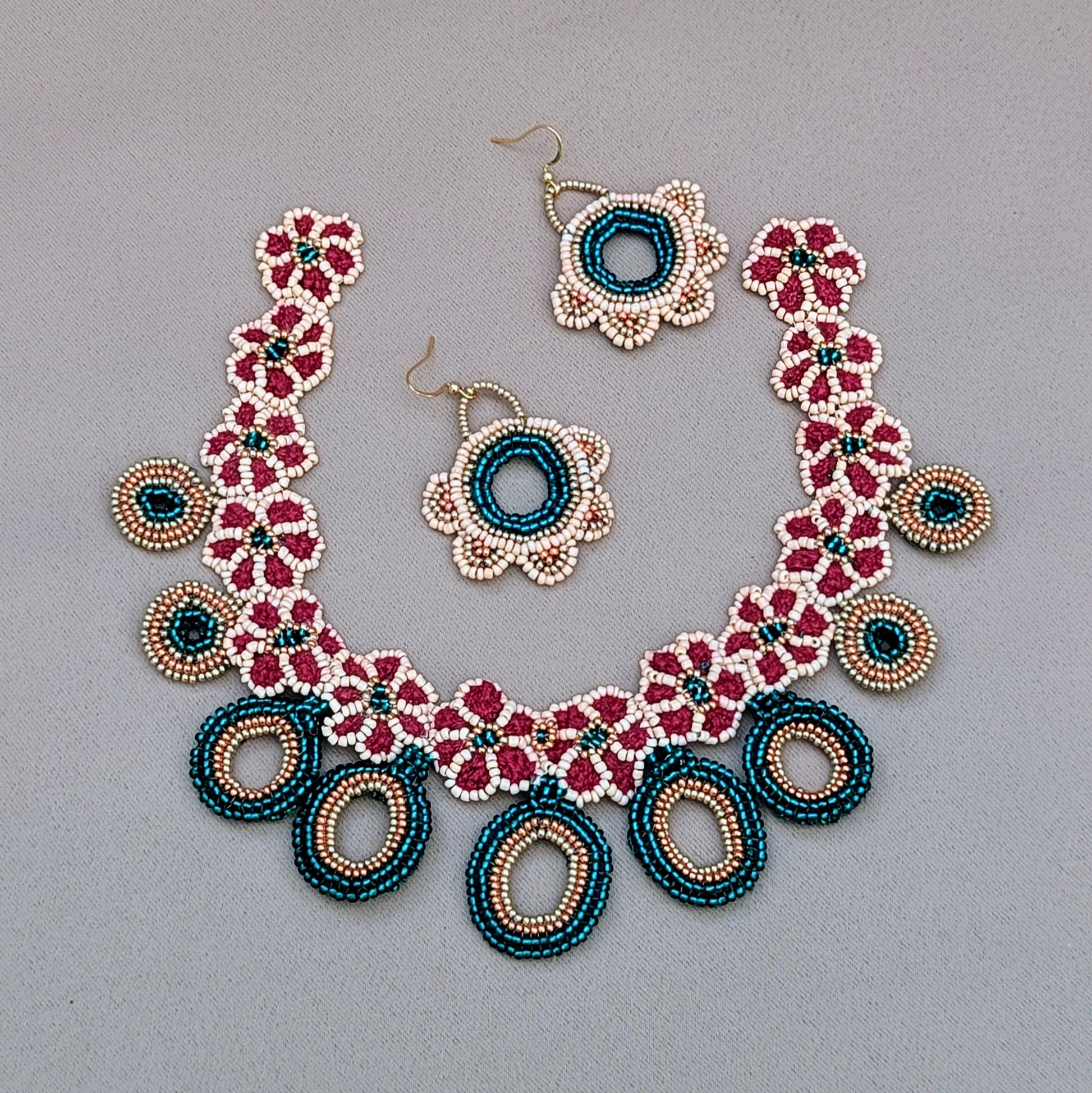 Full Neha bridal jewellery set with earrings and necklace in emerald green, red, peach and gold handcrafted in the UK. Exclusive to Mayaani Jewellery this set comes complete with matching headpiece (maang tikka) and haath phool (bracelet).