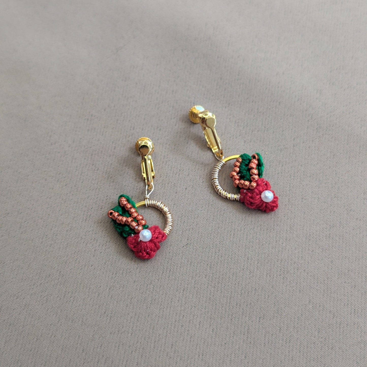 Flat lay view of the red, green, pearl, copper and rose gold Kumkum clip-on earrings designed for premium luxury quality and comfort with sustainability in mind.