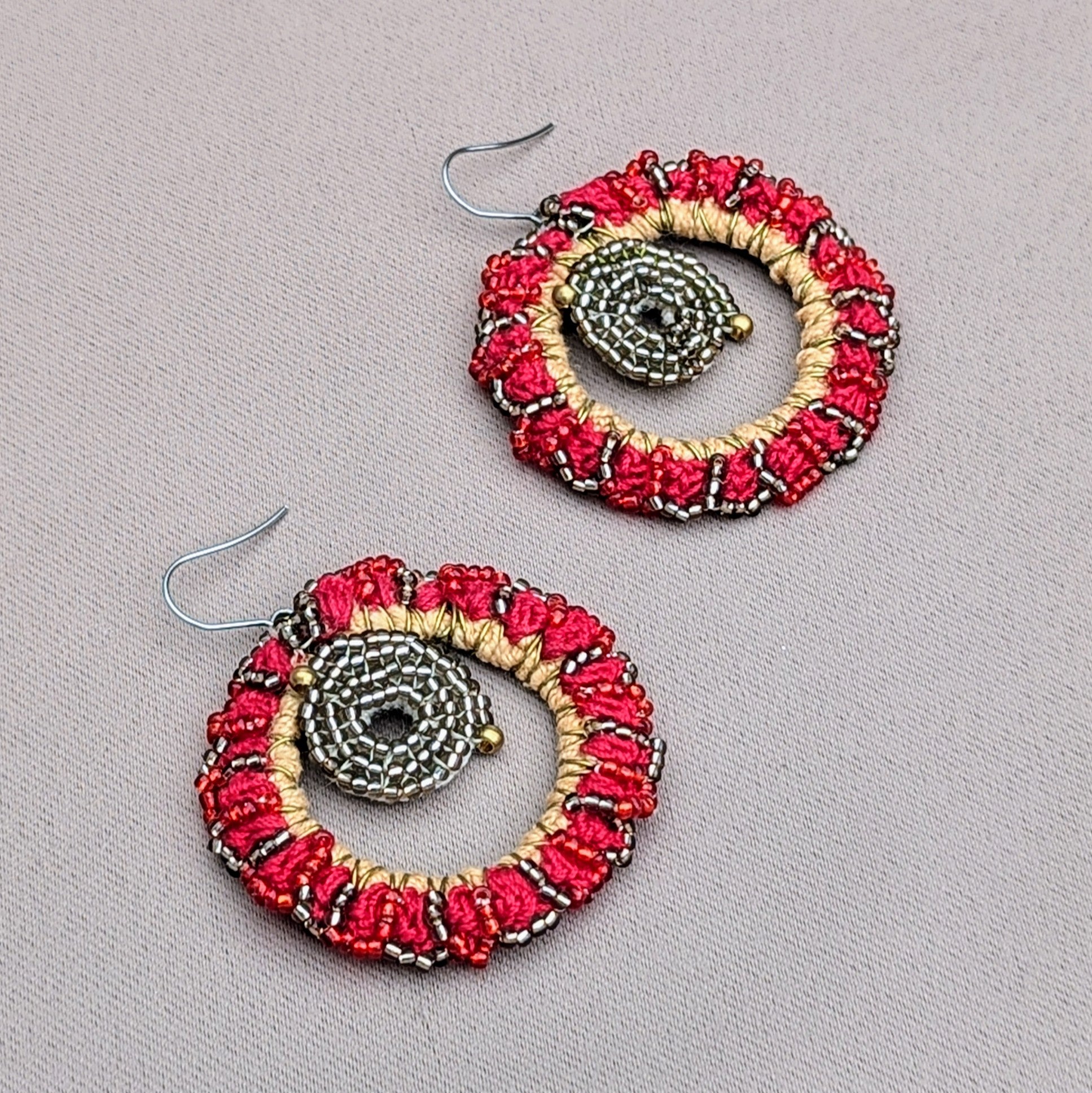 Flat lay of a unique homemade pair of red and gold beaded hoop earrings inspired by the Indian sun.