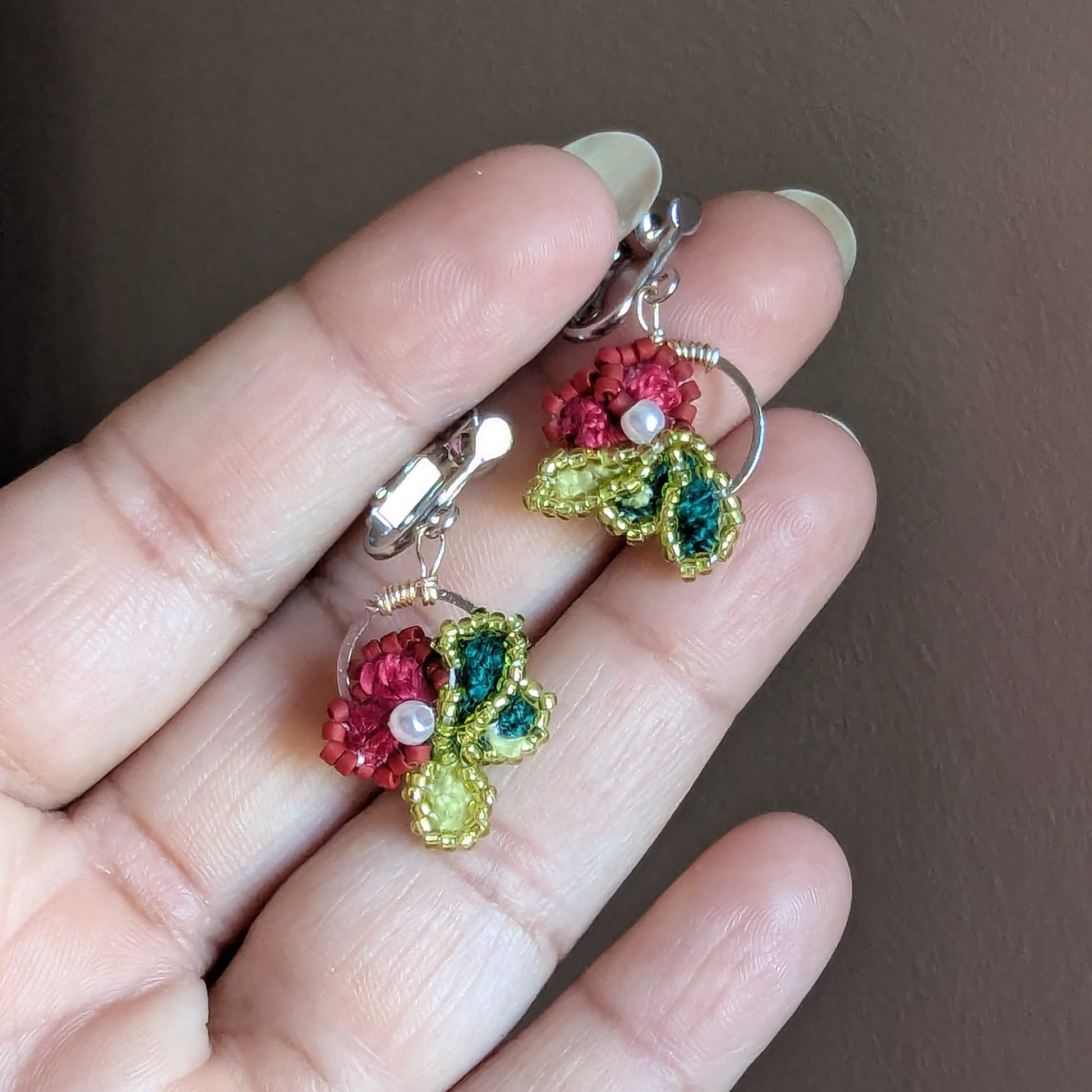 Reva clip-on earrings in palm showing stainless steel hoop frame and rose gold copper wire wrapping at crown.