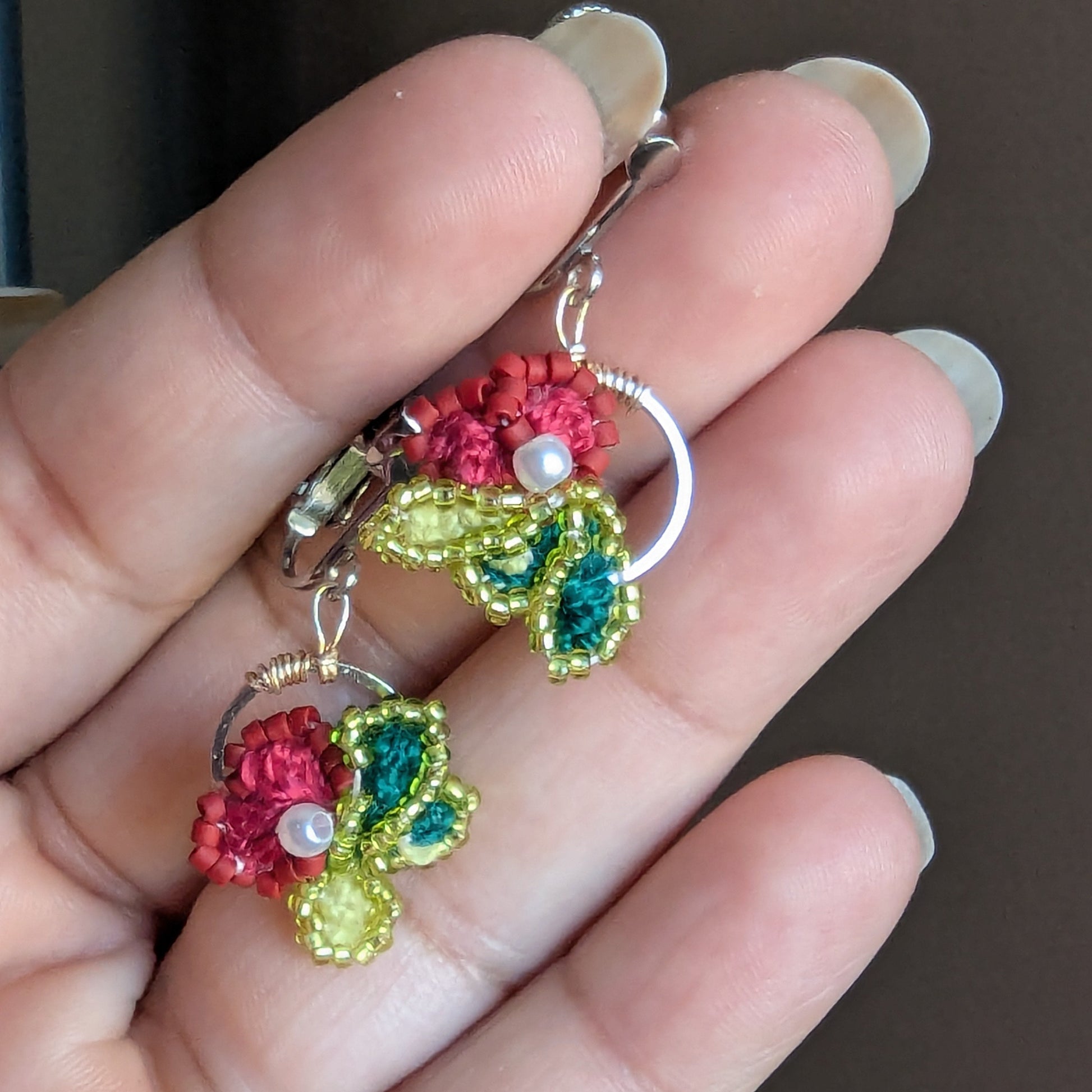 Reva asymmetrical handmade clip-on earrings by Mayaani Jewellery - deep rose crochet flowers with chartreuse and teal leaf detail mirrored across vertical axis.
