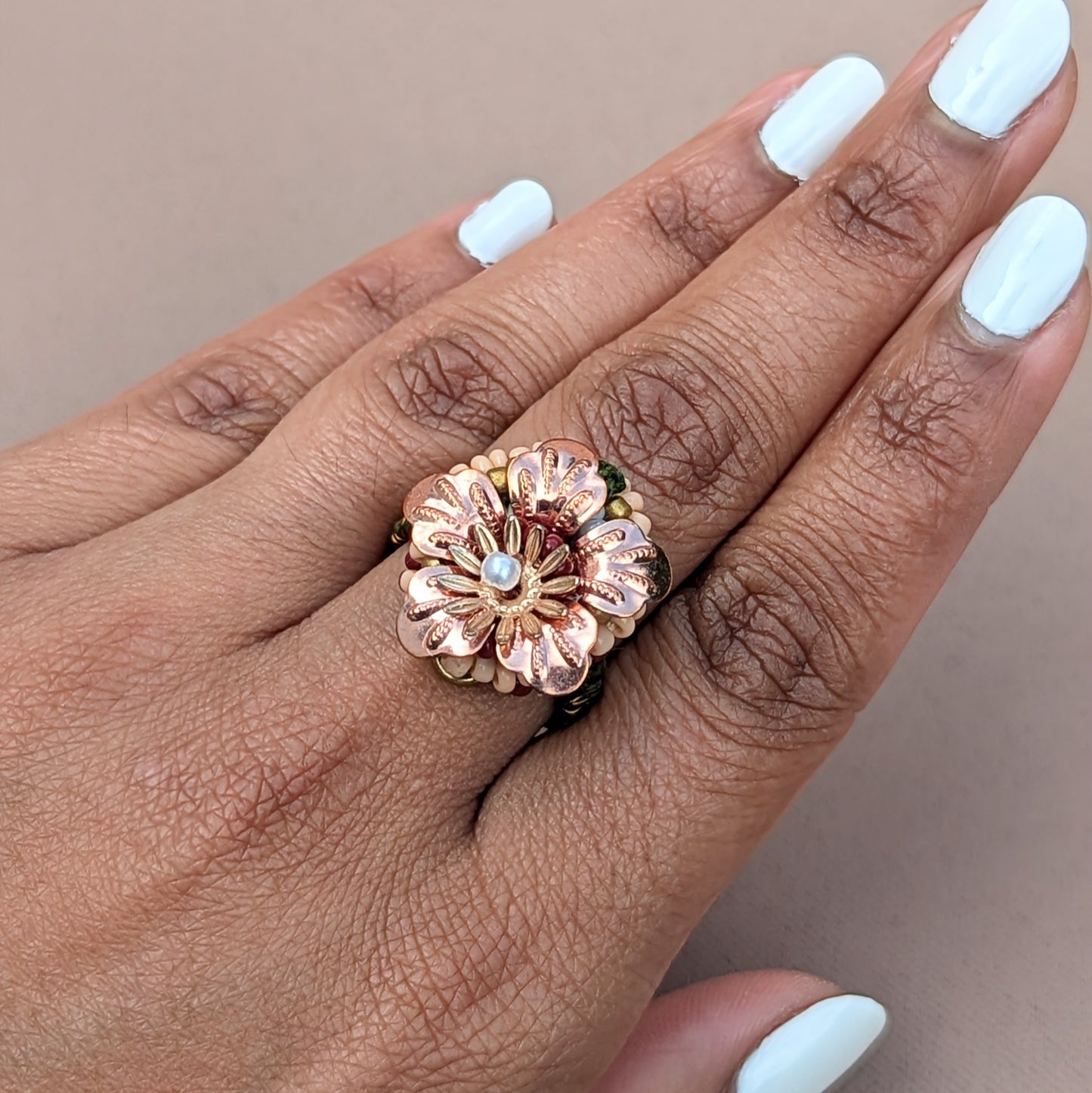 A South Asian woman's hand modelling a rose gold plated flower ring handcrafted by sustainable artisan Indian brand Mayaani Jewellery UK.