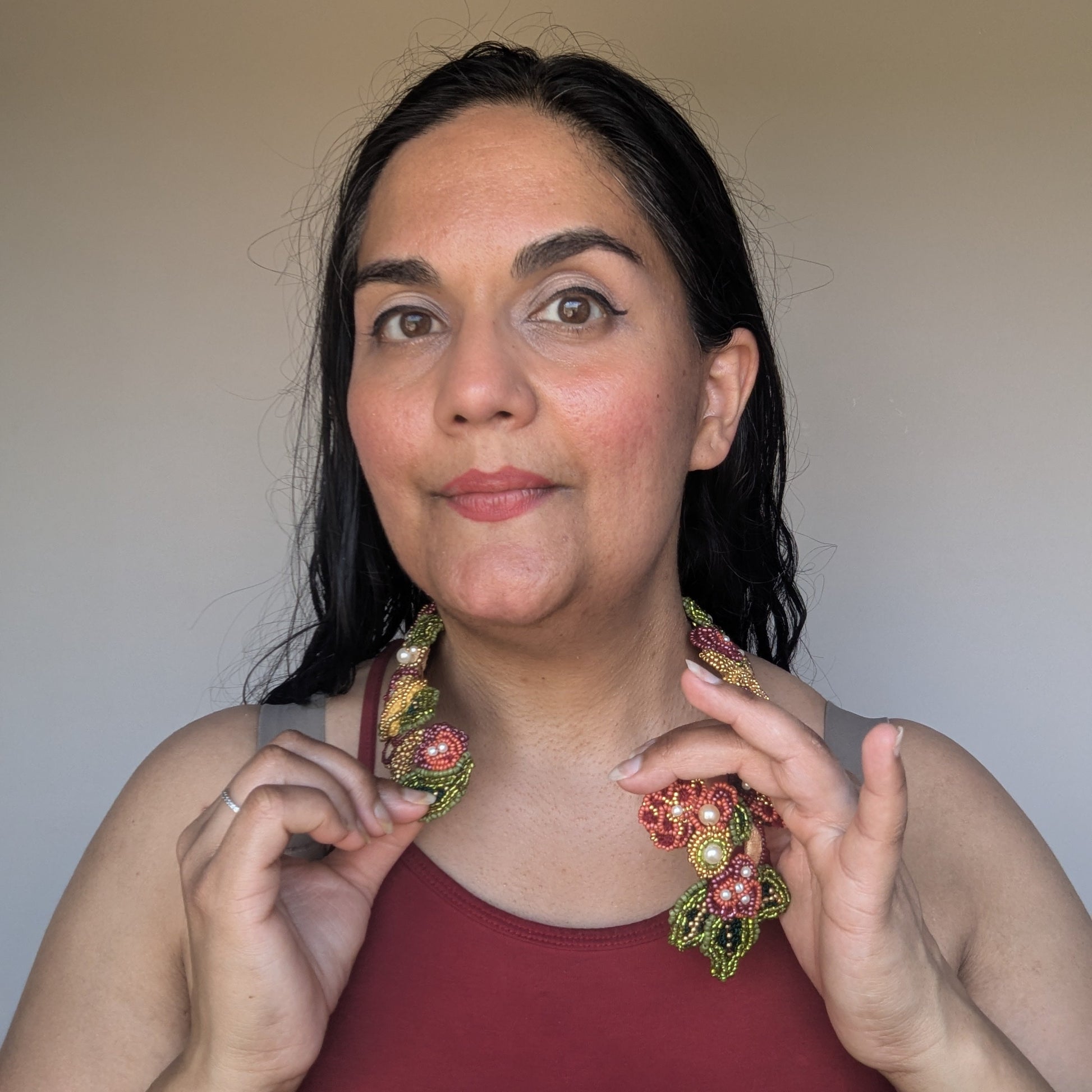 Megha smiling showcasing the front facing clasp of the one-of-a-kind Rukmini couture necklace exclusive to Mayaani Jewellery UK. 