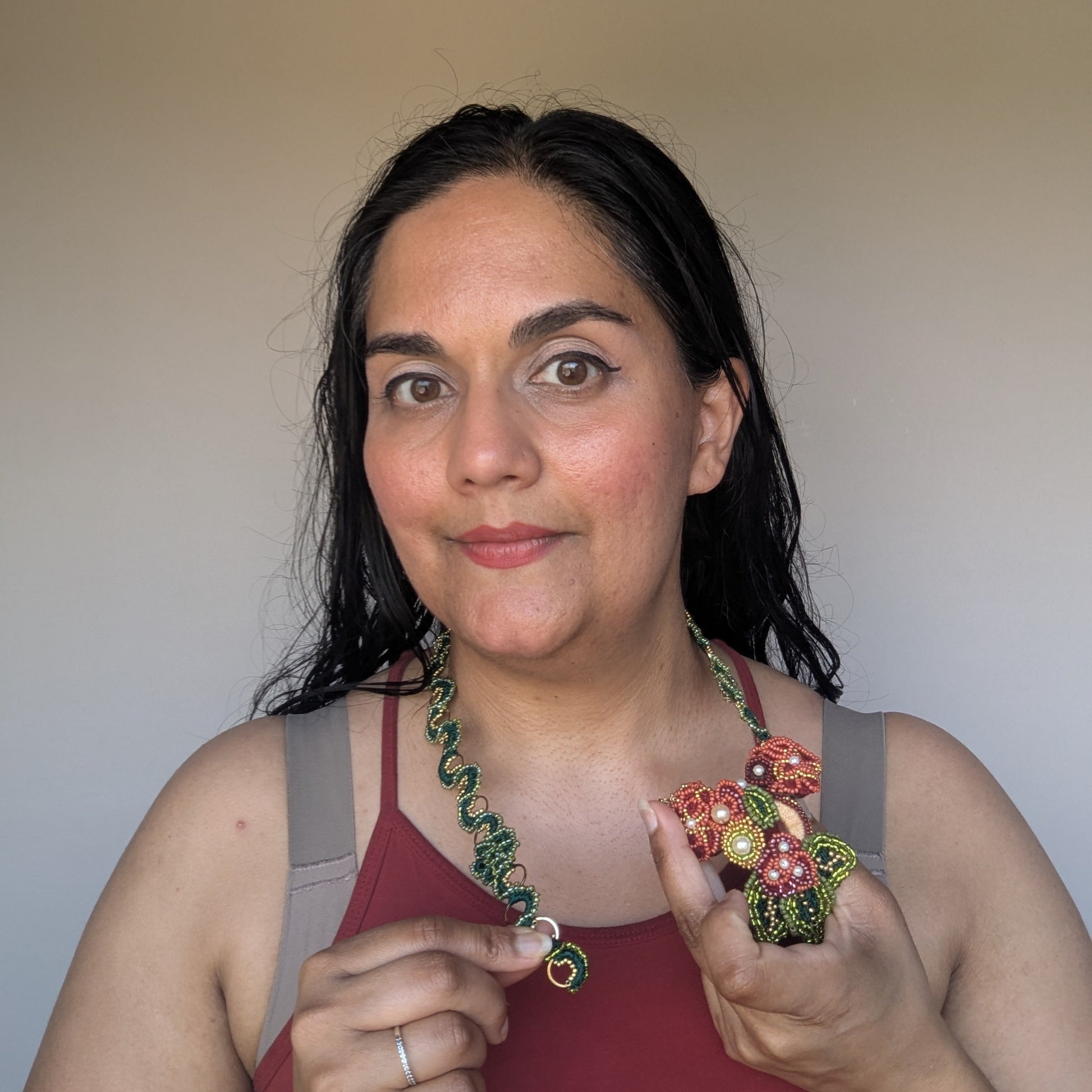 Megha of Mayaani Jewellery UK showcasing the innovative Rukmini red, green, gold and yellow front facing detachable pendant clasp transforming statement occasion wear to everyday style.