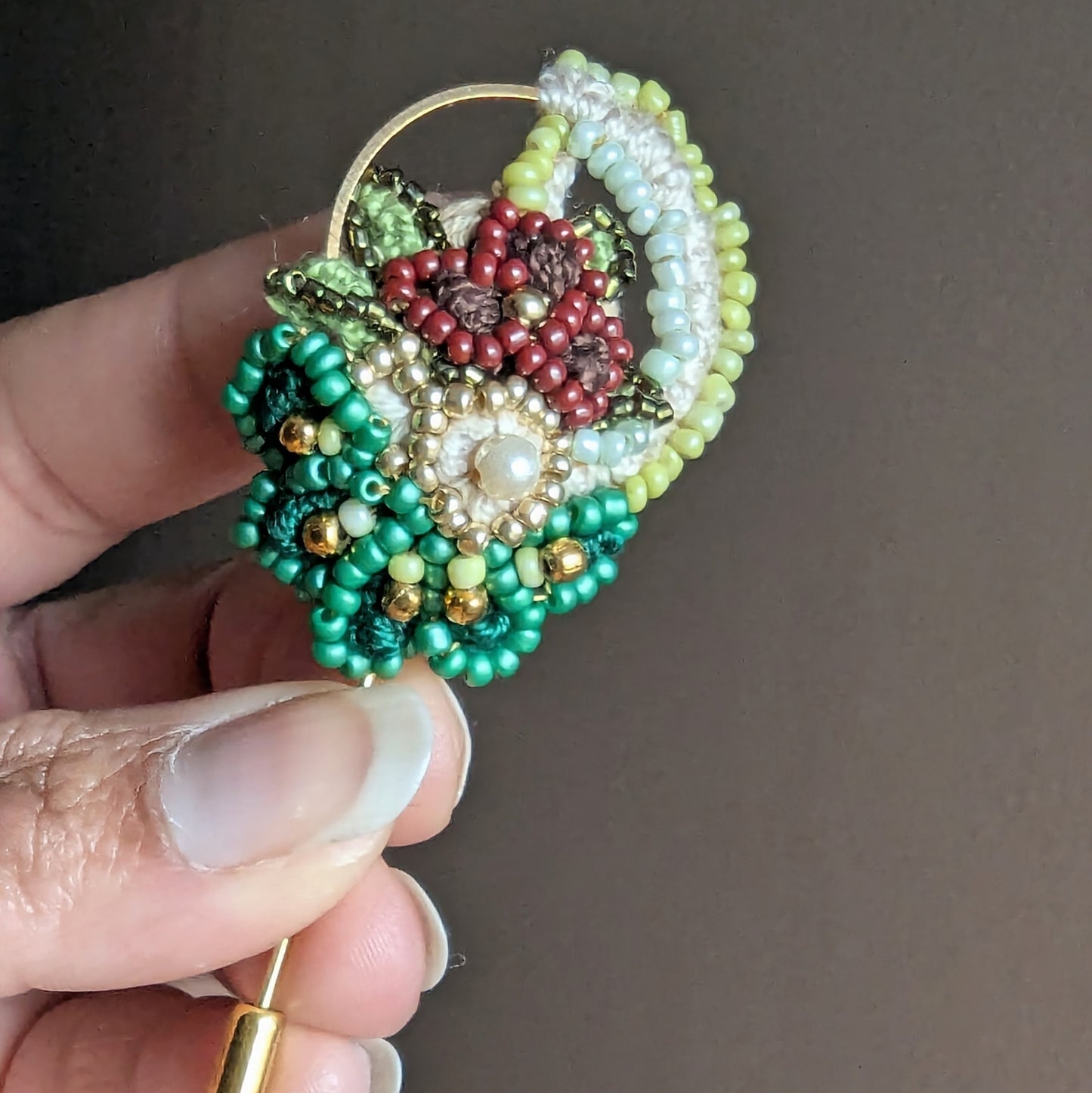 Sarika handmade beaded brooch pin featuring emerald green Miyuki beads, coral beadwork and gold hoop detail.