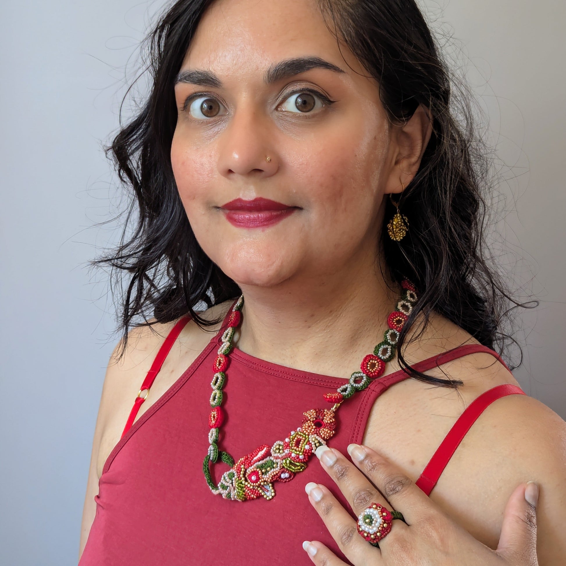 Close up view of Megha of Mayaani Jewellery modelling the ring and necklace elements of the Shreya 5-in-1 red, gold and green Indian hand bracelet exclusively handcrafted in the UK.