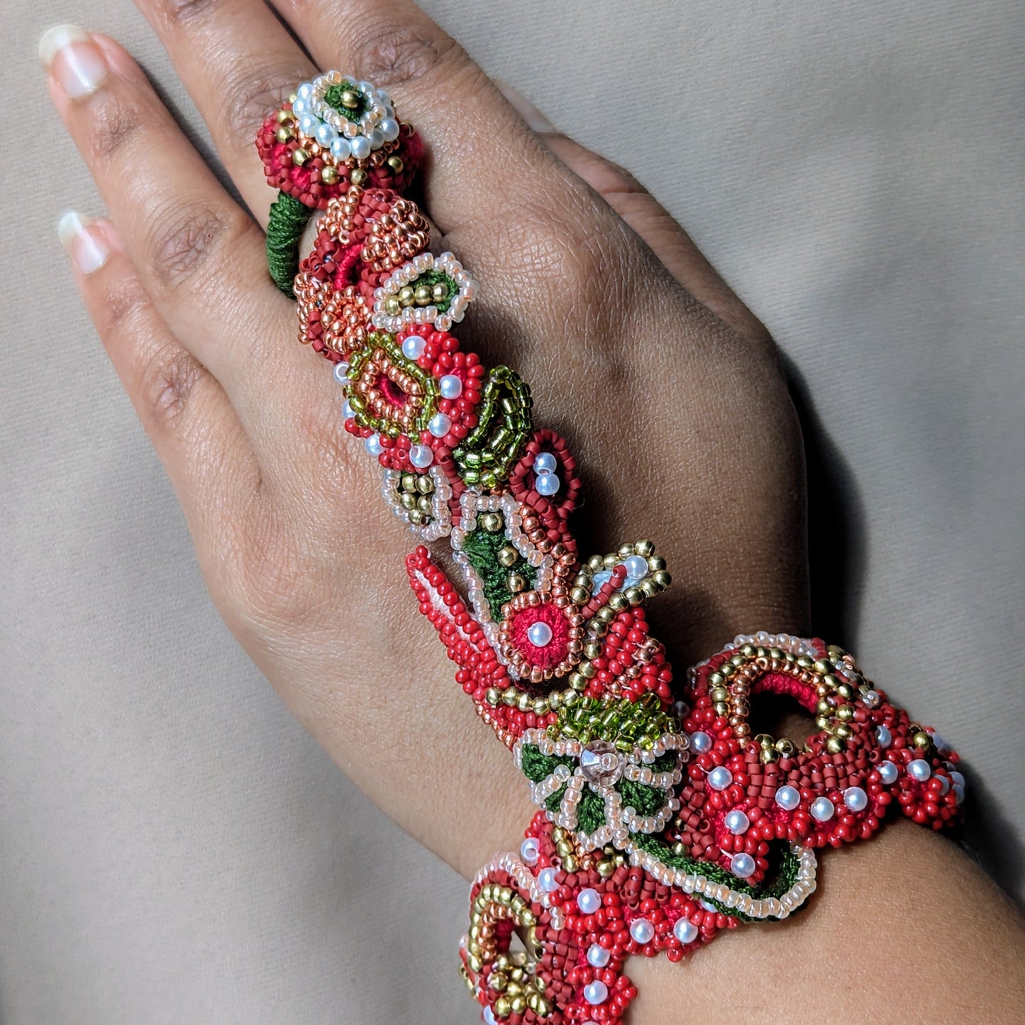 Close up of a hand modelling the Shreya 5-in-1 Indian hand bracelet in traditional Indian bridal colours.